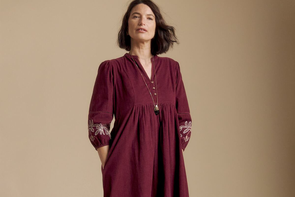 A woman in a long, dark red Julipa dress with embroidered sleeves.