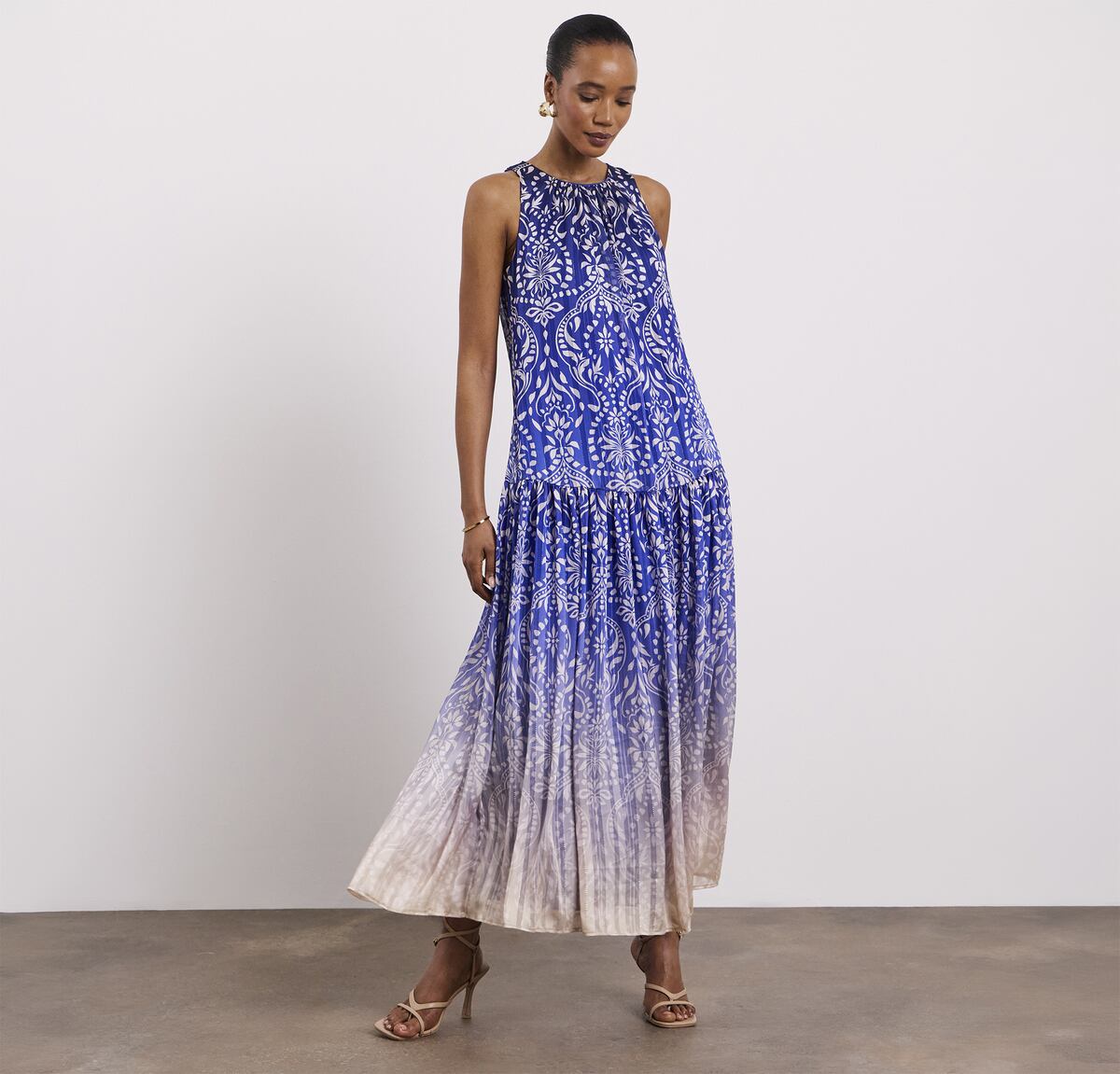 A lady stood wearing a Joanna Hope printed halter neck dress with metallic thread