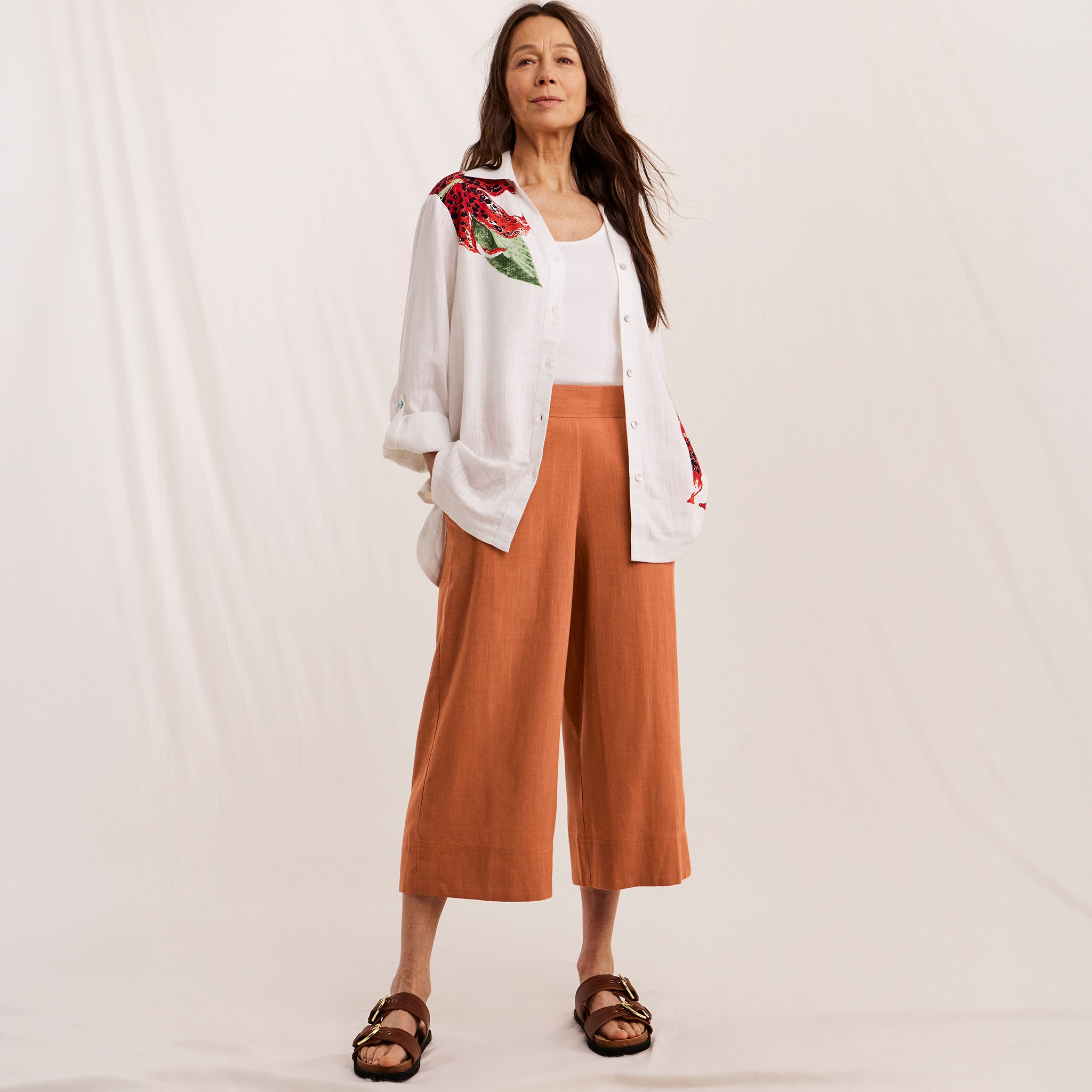 Woman wearing Julipa summer outfit, white slinen shirt and orange trousers