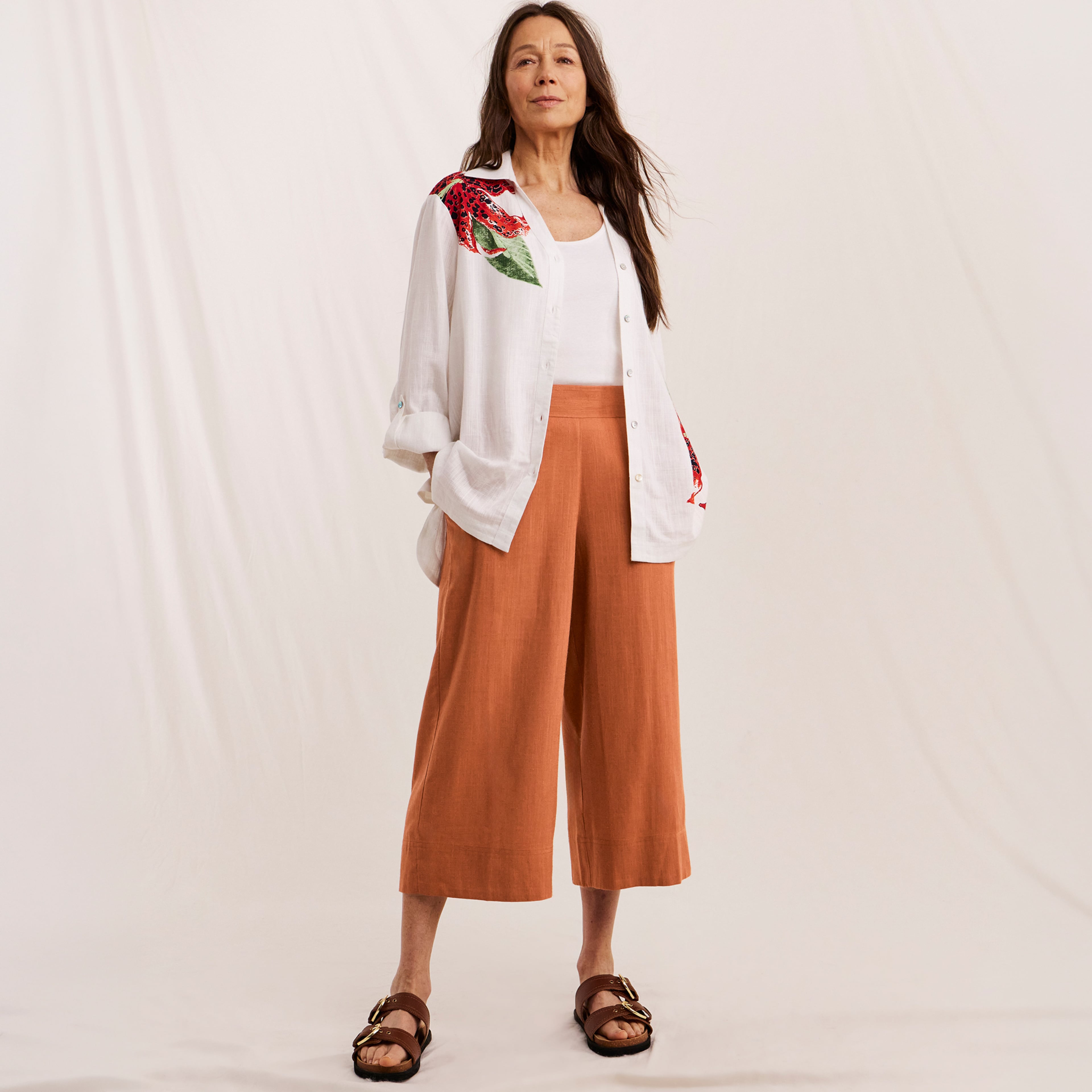 Woman wearing Julipa summer outfit, white slinen shirt and orange trousers