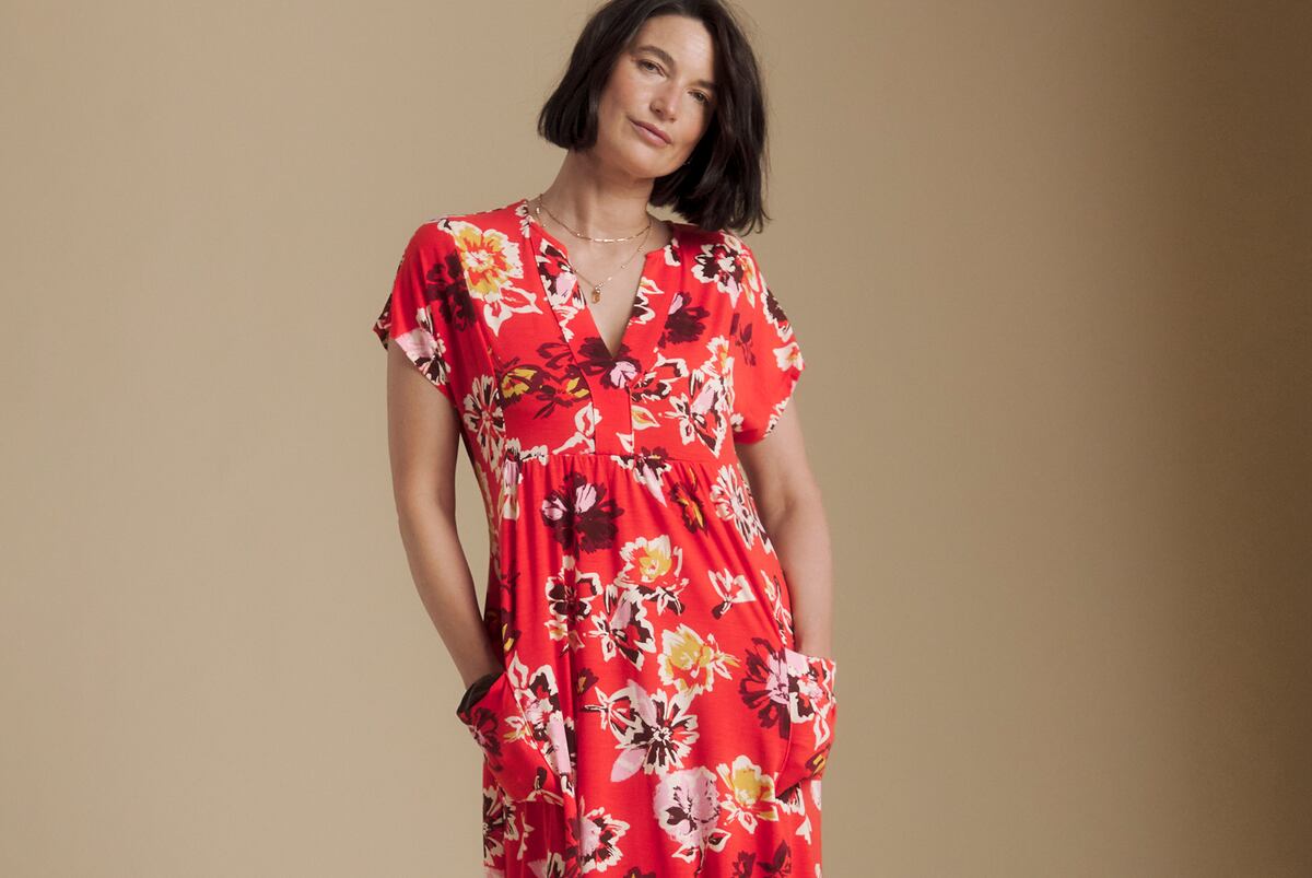 Person wearing a bright red Julipa floral midi dress with a V-neckline and short sleeves, standing with hands in pockets