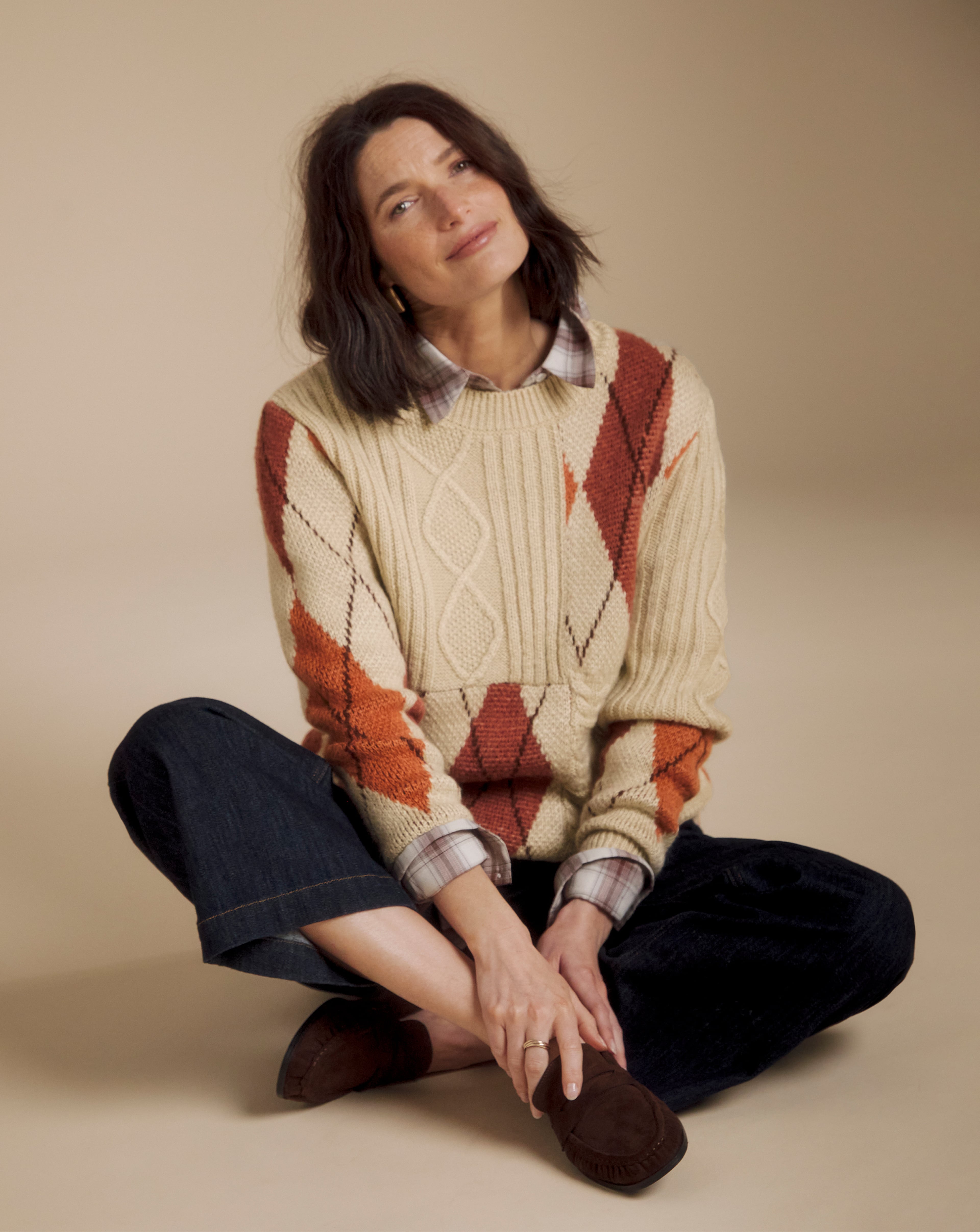 Model is wearing a Julipa Cable Argyle jumper with a pair of dark denim jeans.