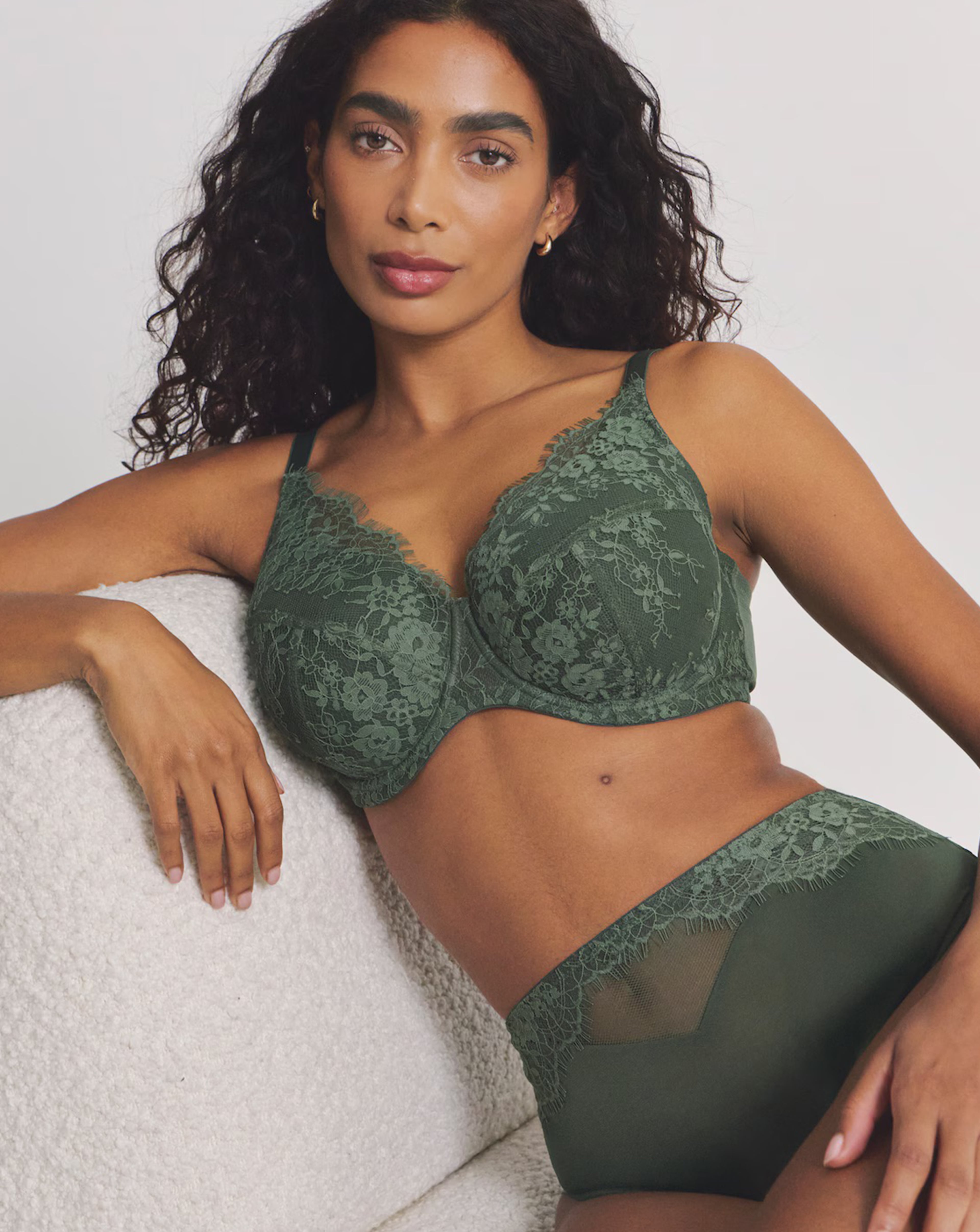 A model is wearing a green Pretty Secrets full cup lace padded bra with matching lace full brief knickers.