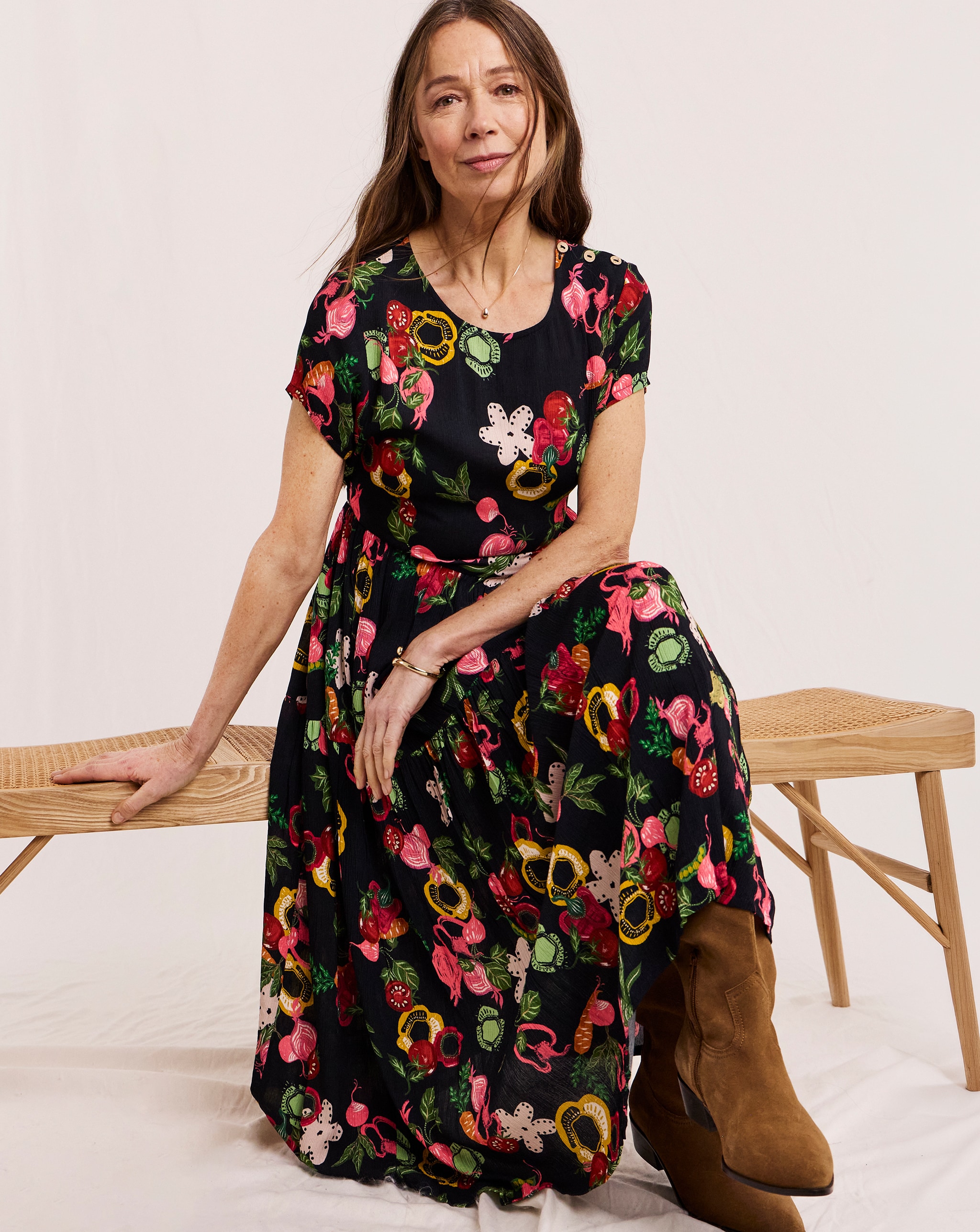 A model sat on a bench seat wearing a Julipa midi dress in navy print