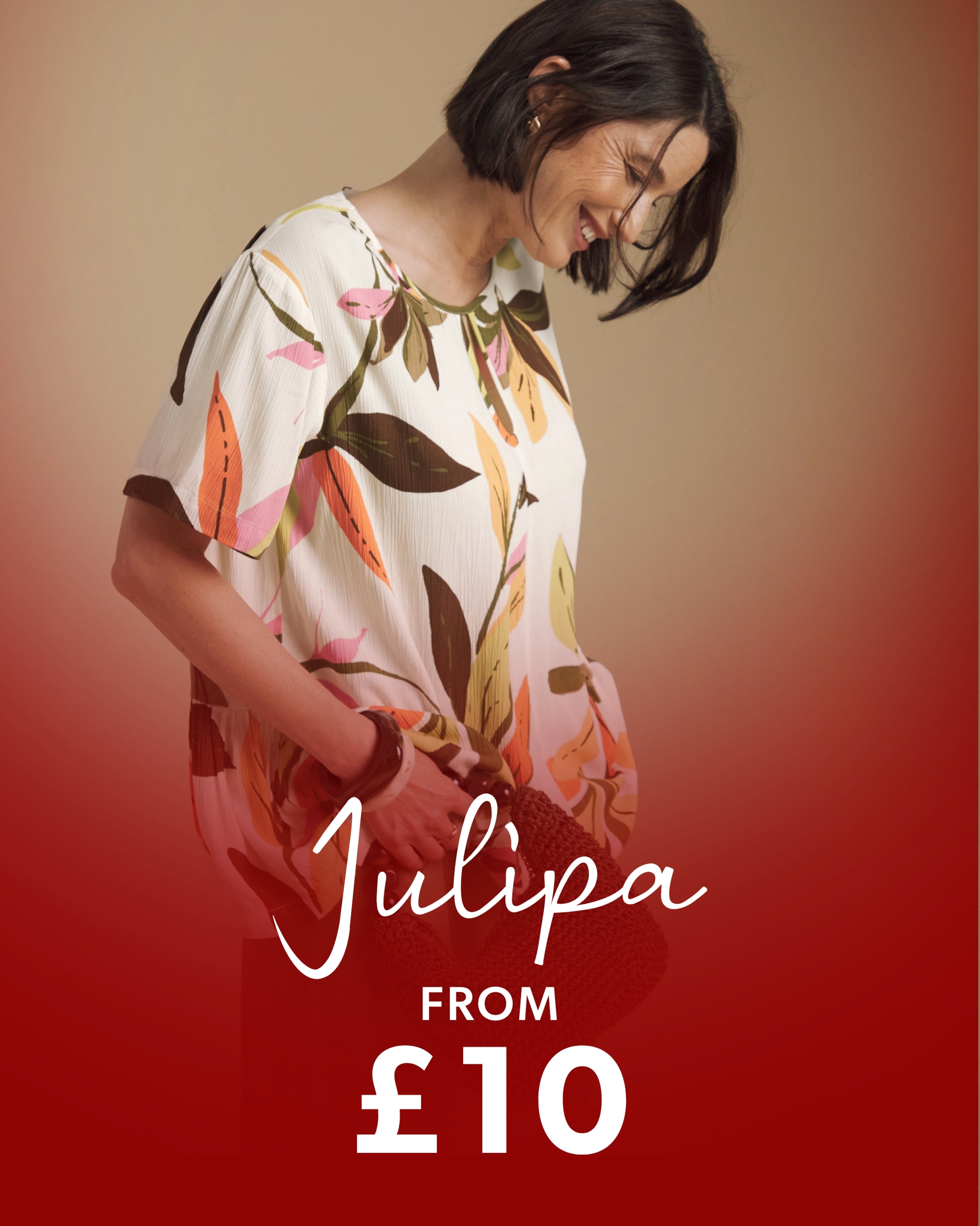 Person wearing a Julipa floral print top holding a woven handbag.