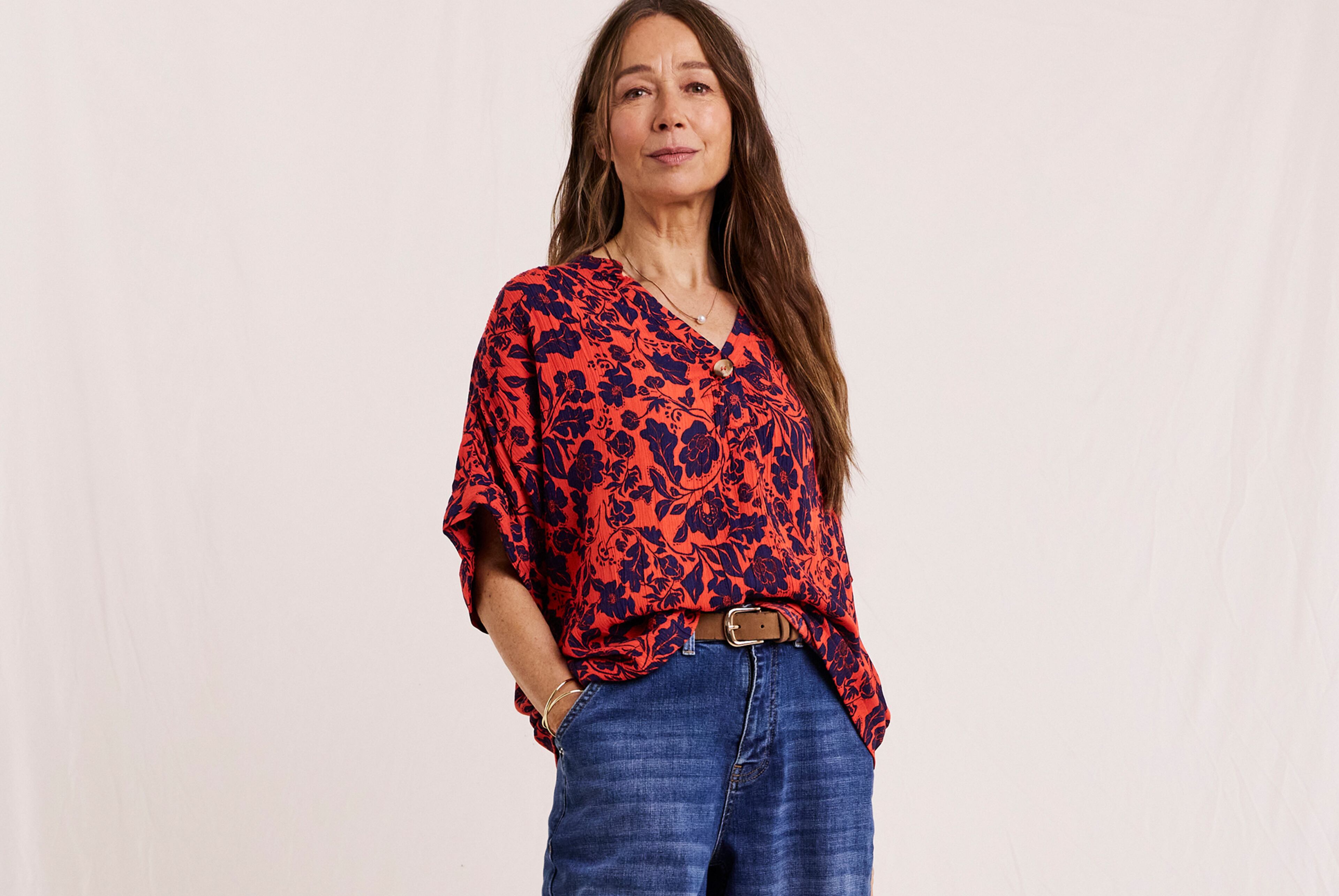 Model wearing a Julipa crinkle short sleeve top with a rust-coloured print, and blue jeans. 