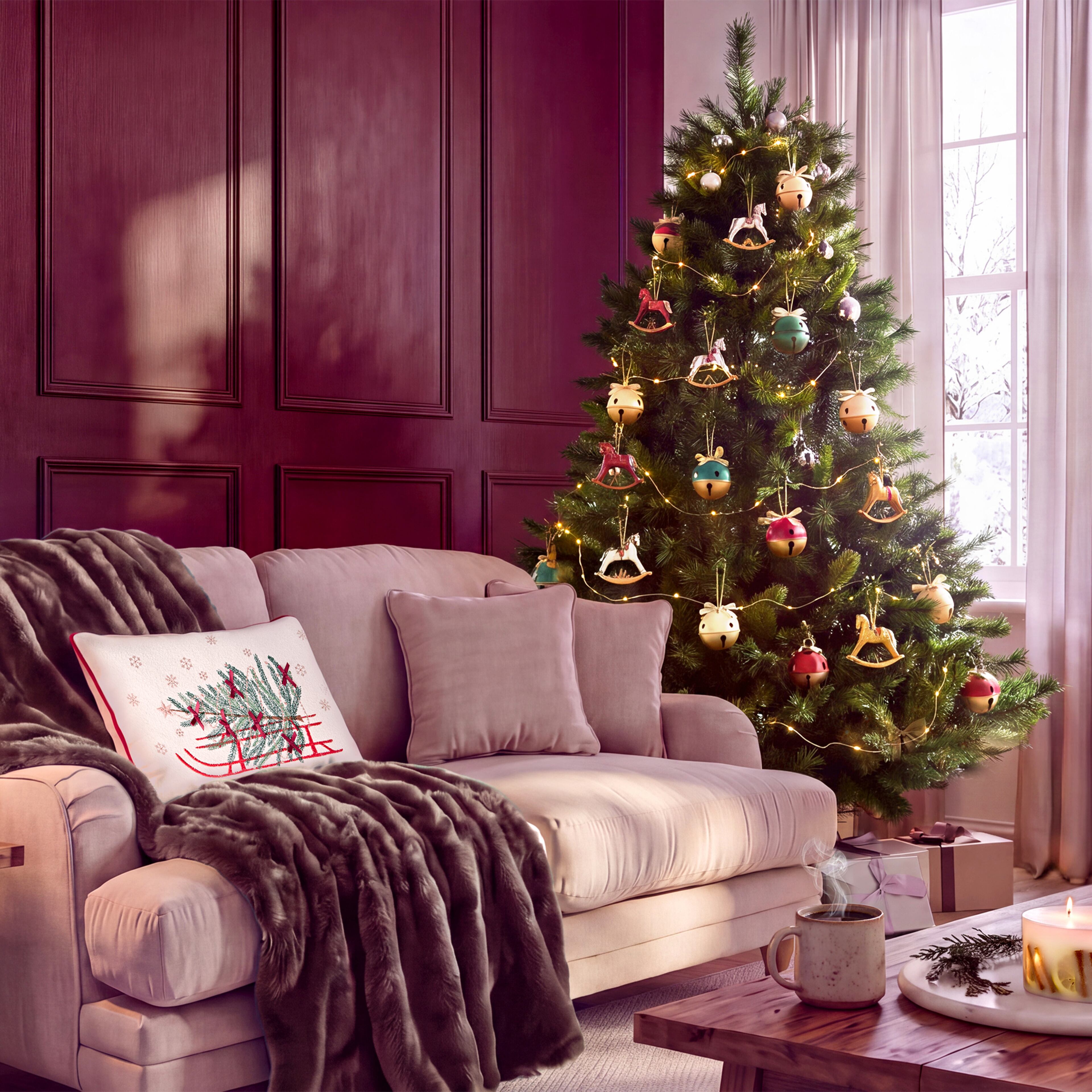 Decorated Christmas tree with warm lights beside a sofa in a cosy living room.