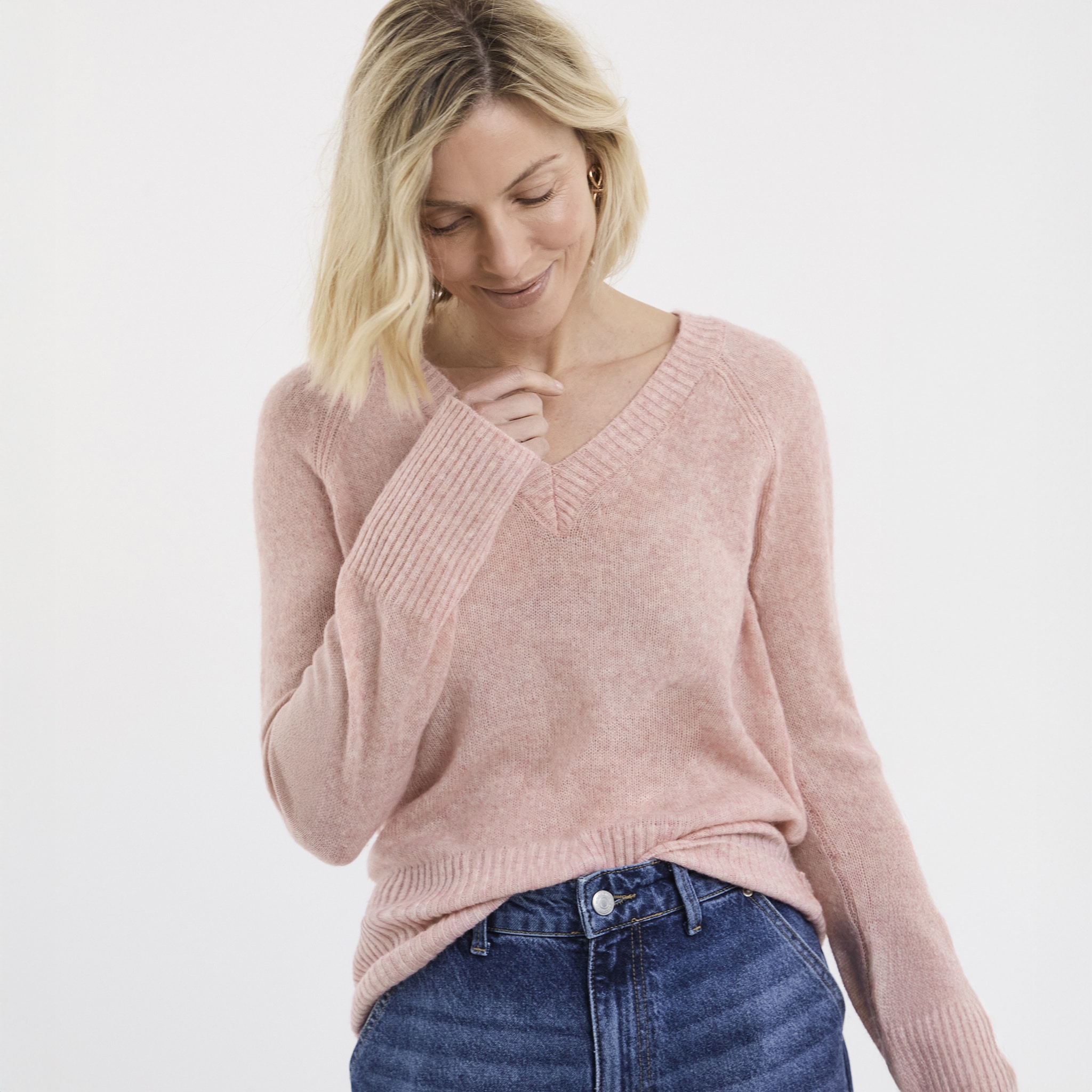 A lady wearing a dusky pink v neck knitted jumper.