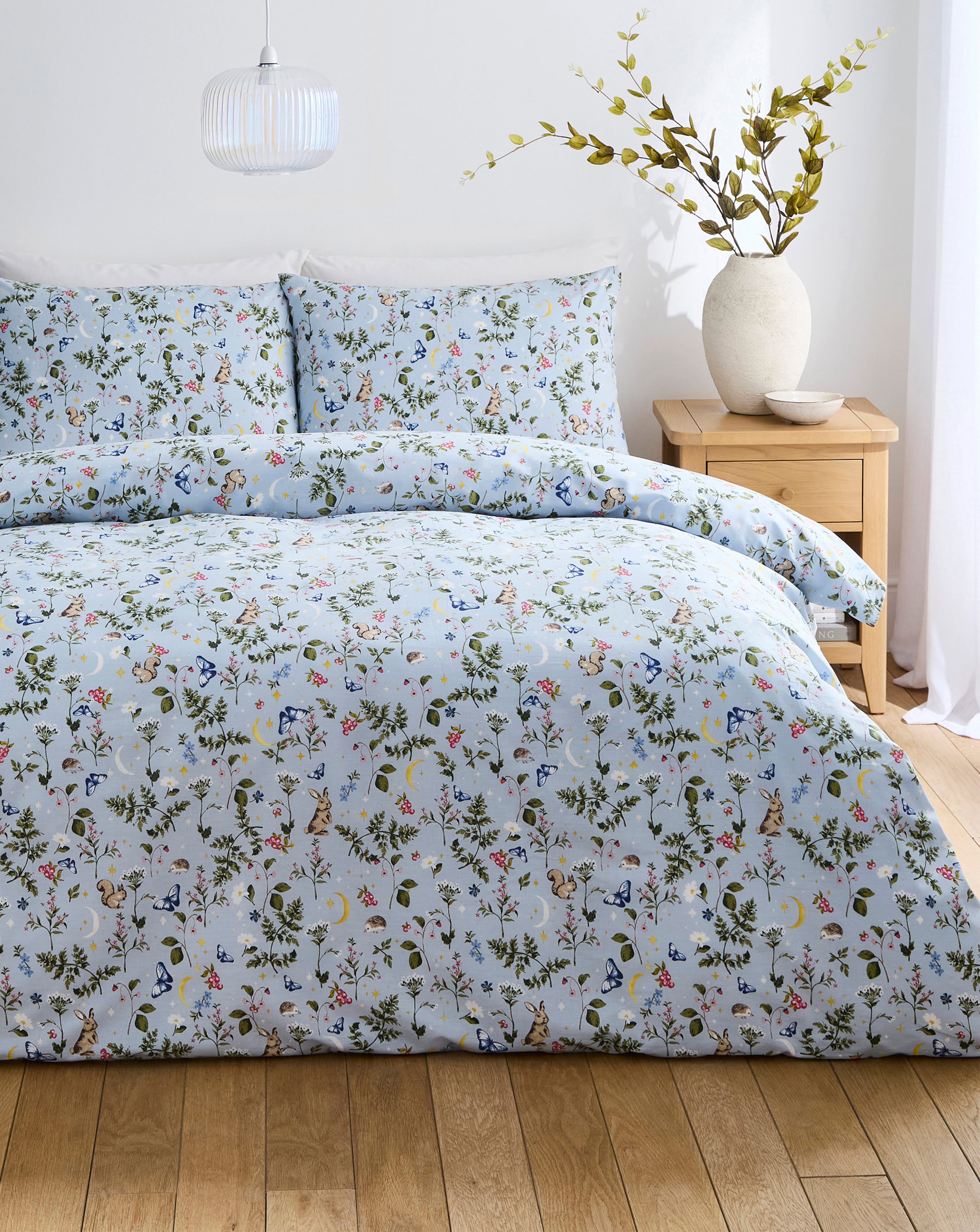 A double bed with a blue summer meadow duvet cover set