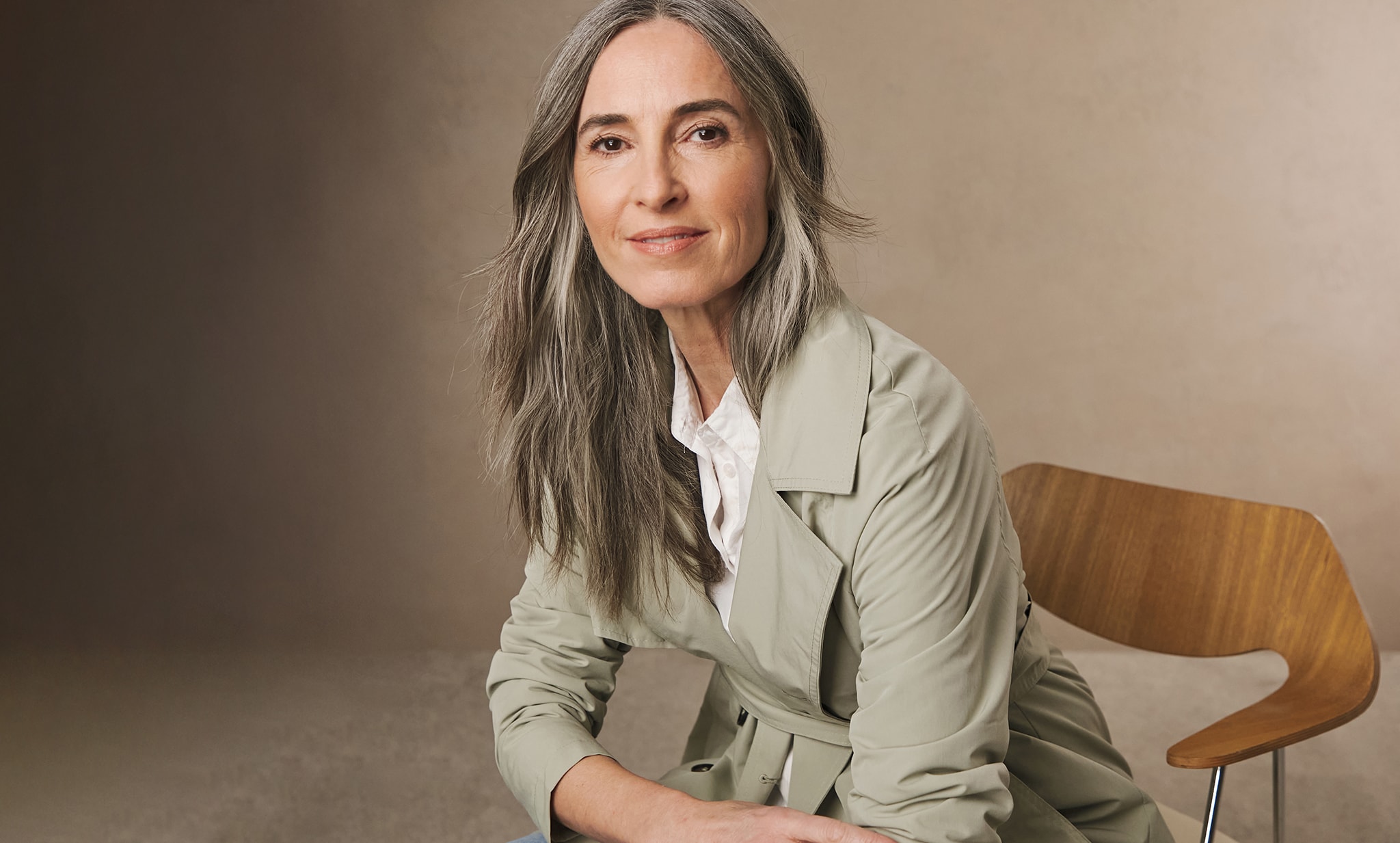 A woman sat wearing a light green rain mac and white blouse