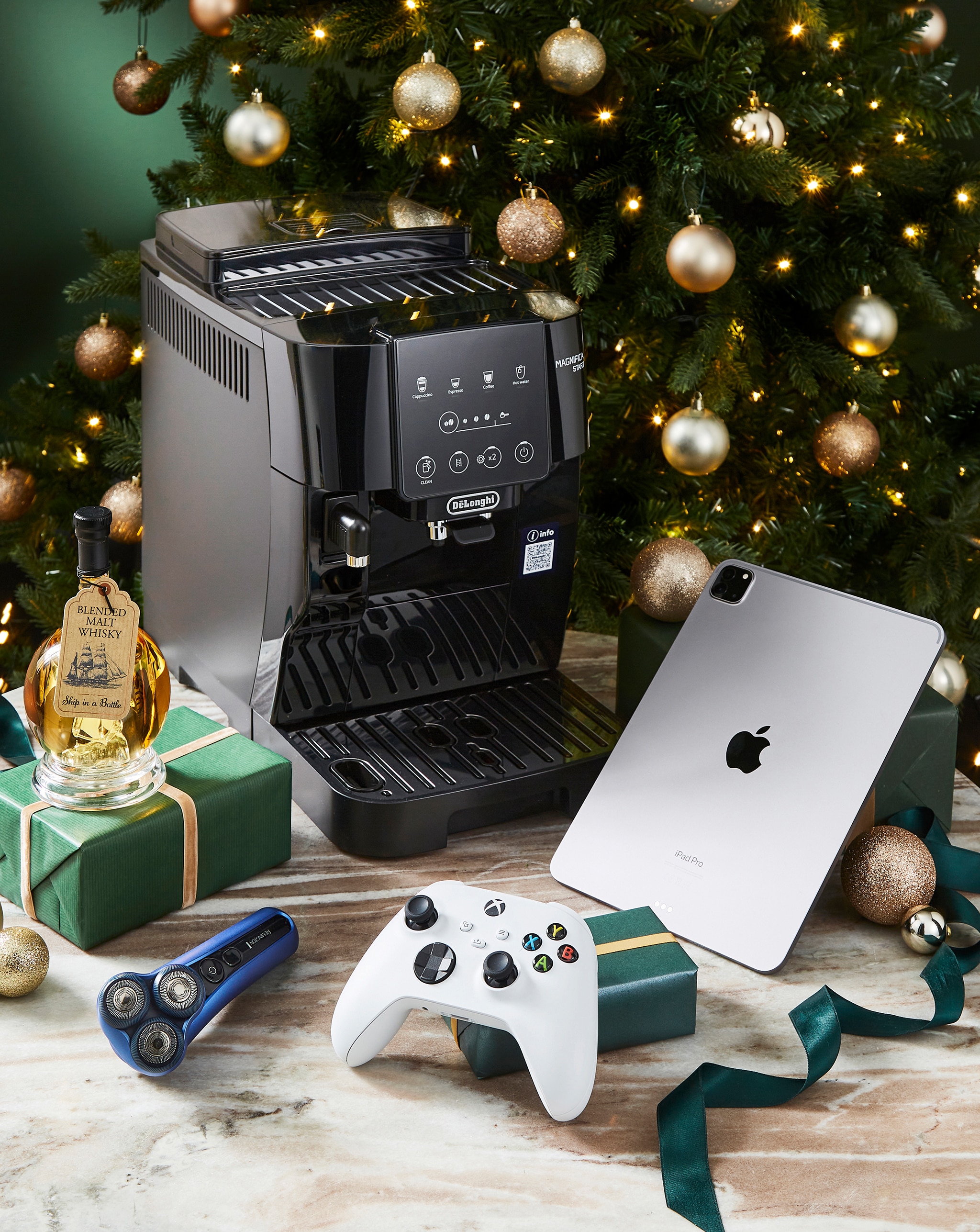 Tech products including a PlayStation 5 and Nintendo Switch 2, in front of a Christmas tree.