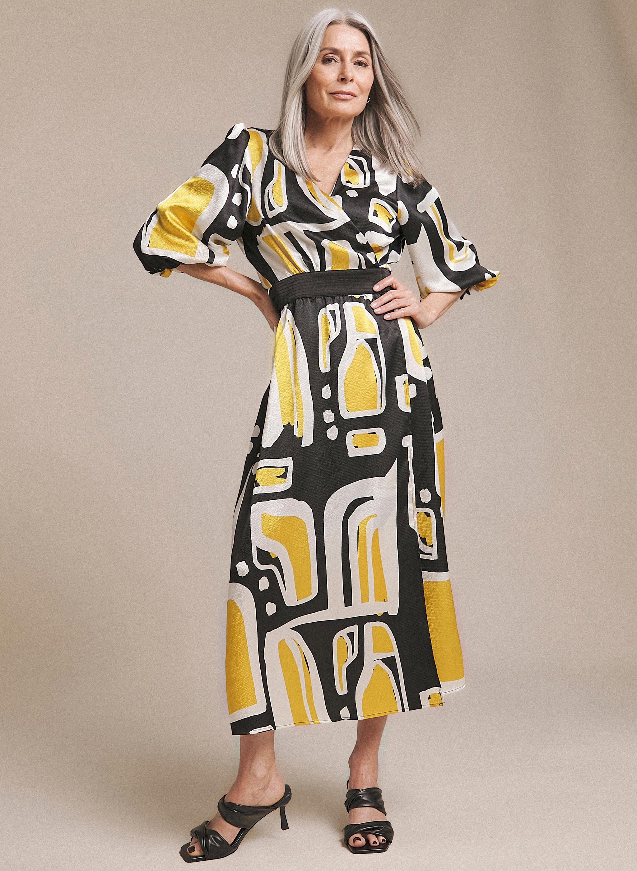 Woman stood wearing a black and yellow patterned long dress