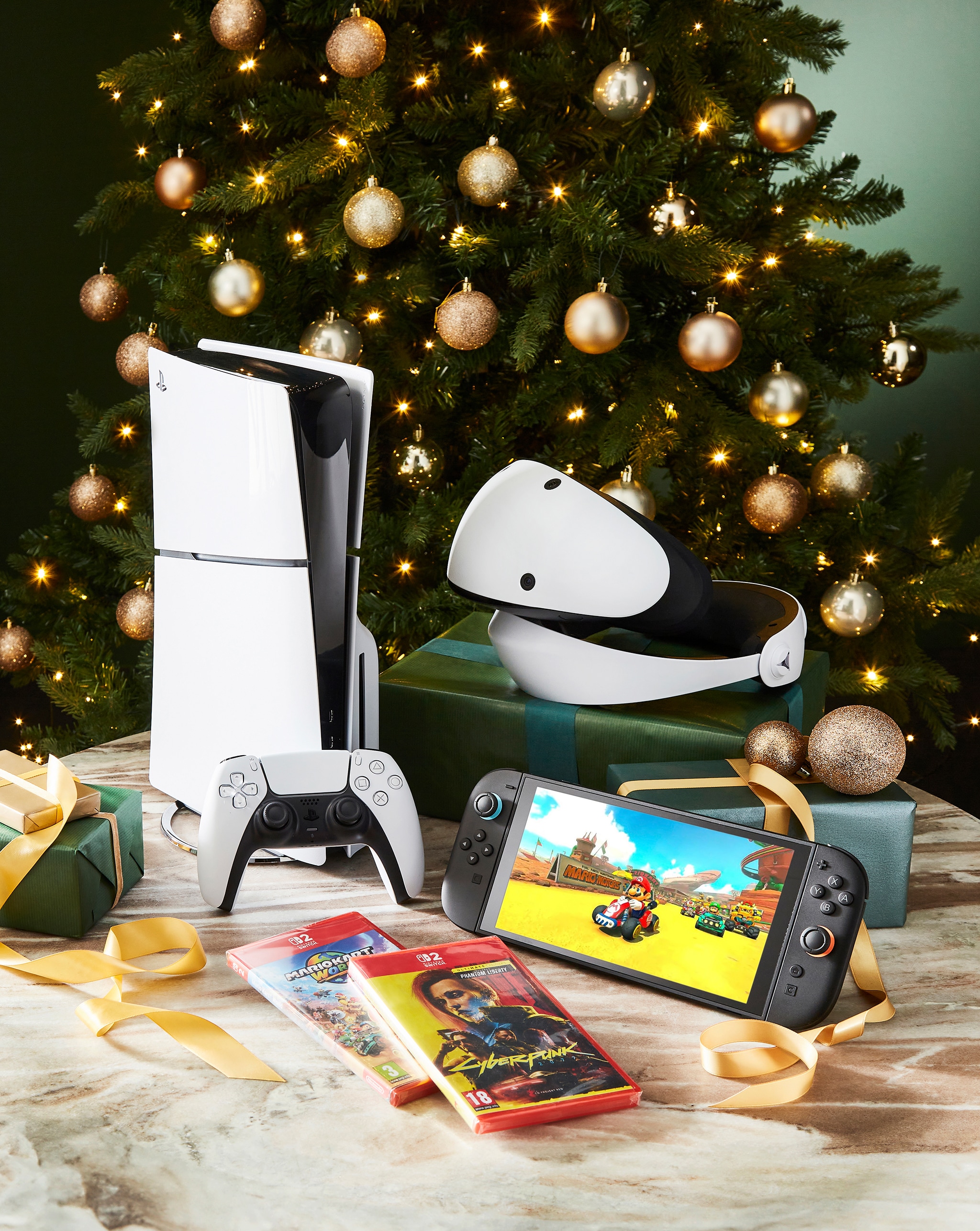 Tech products including a PlayStation 5 and Nintendo Switch 2, in front of a Christmas tree.