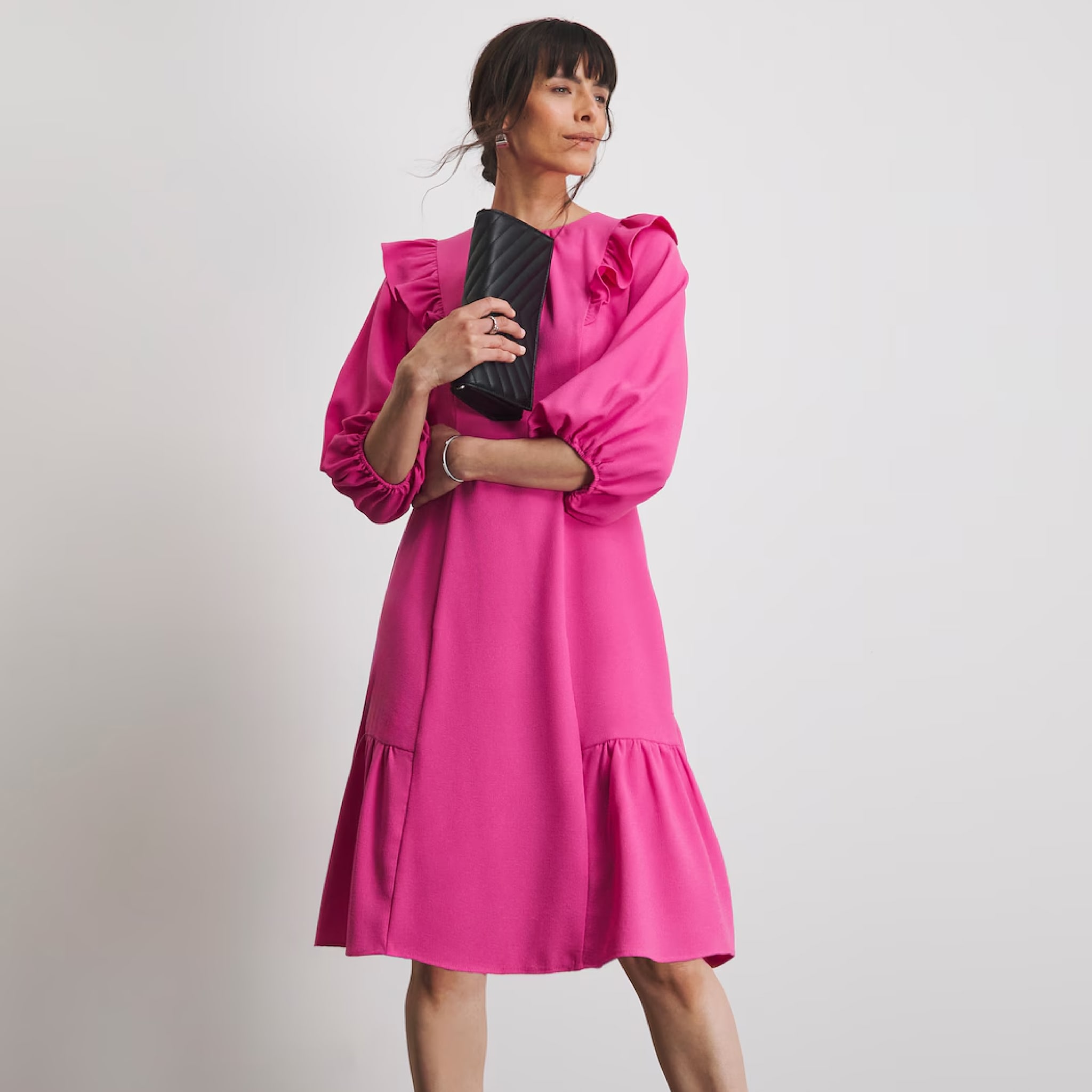 A woman stood wearing a pink ruffle dress