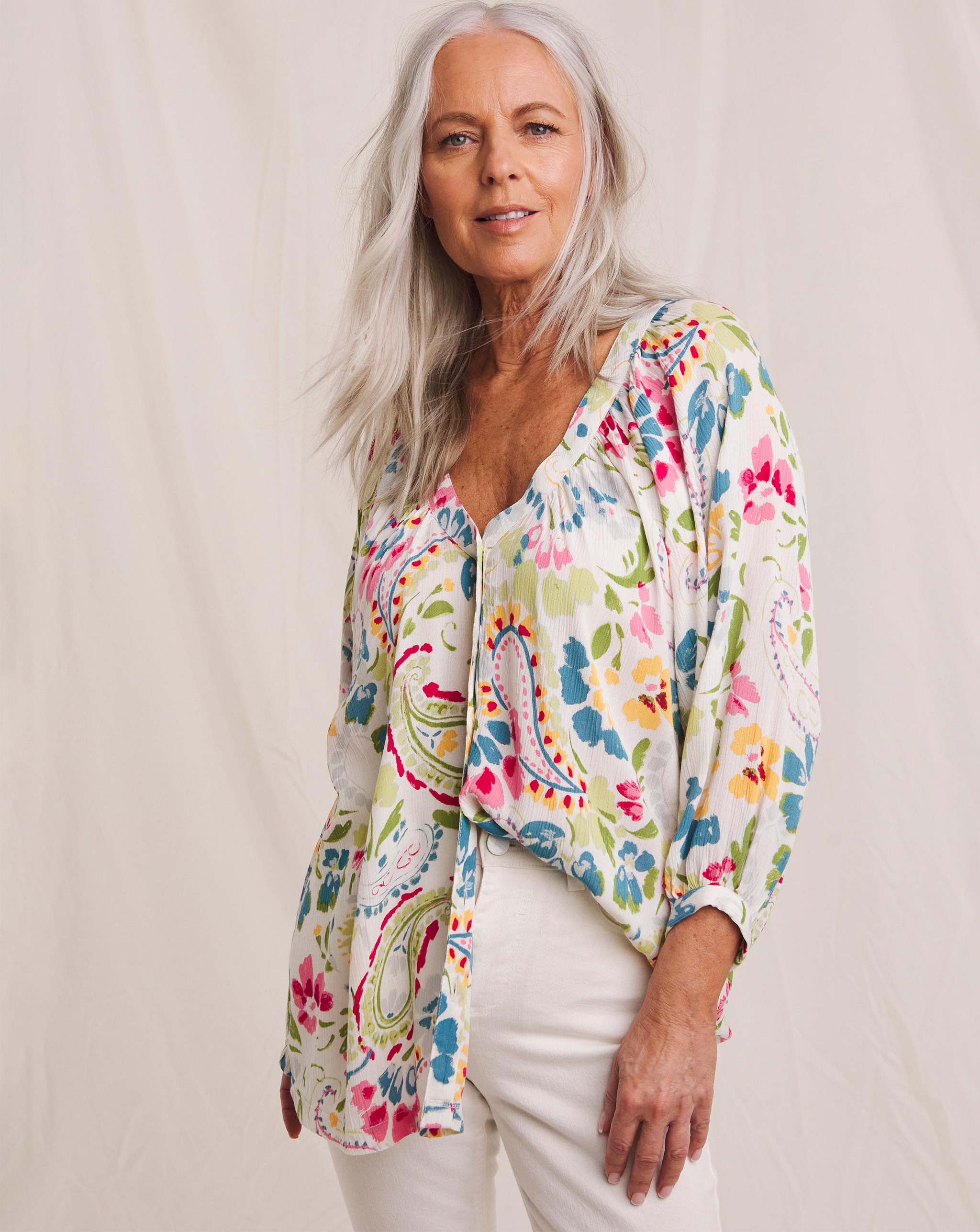 A woman wearing a Julipa printed blouse and white jeans