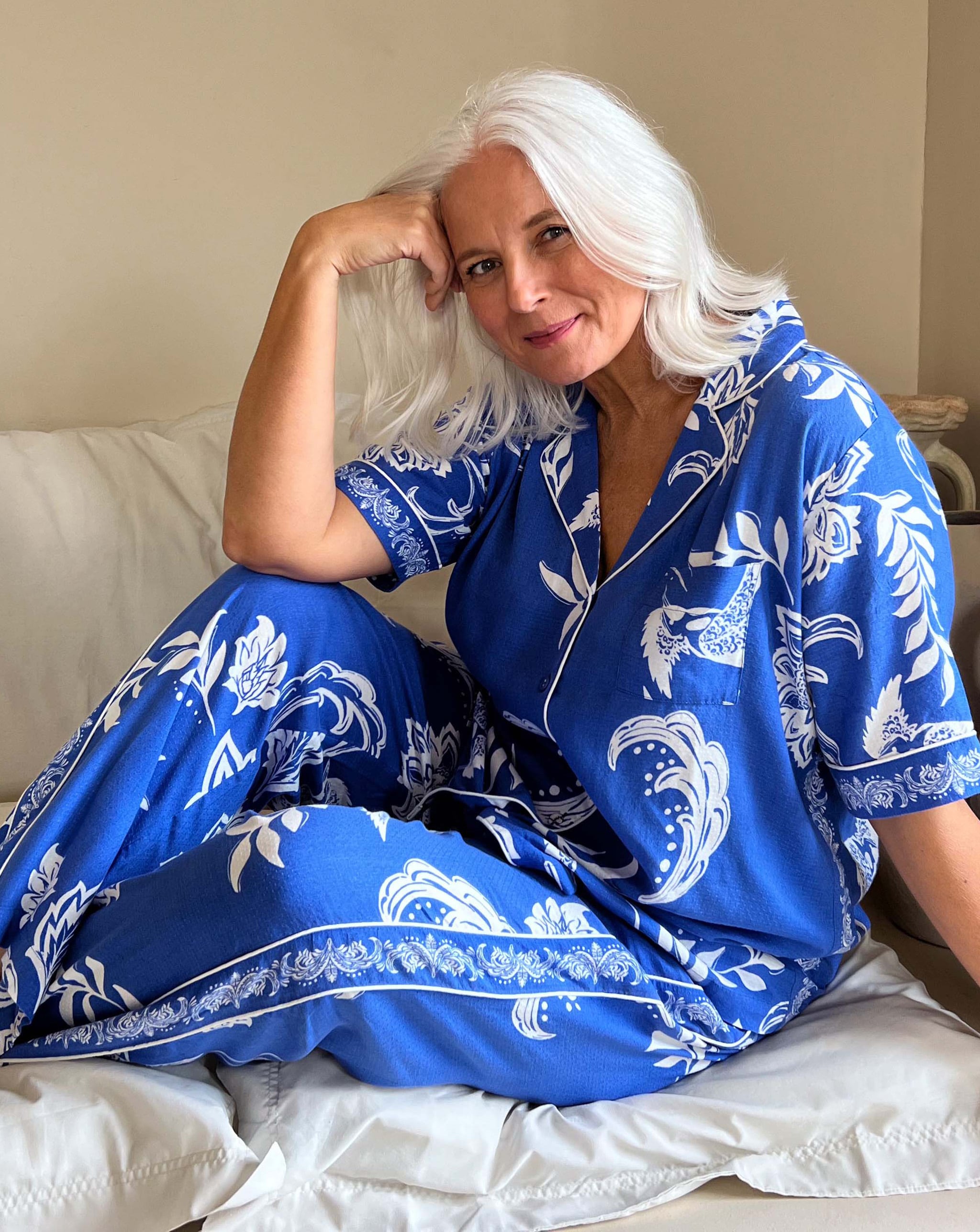 Model sat on a bed wearing blue nightwear