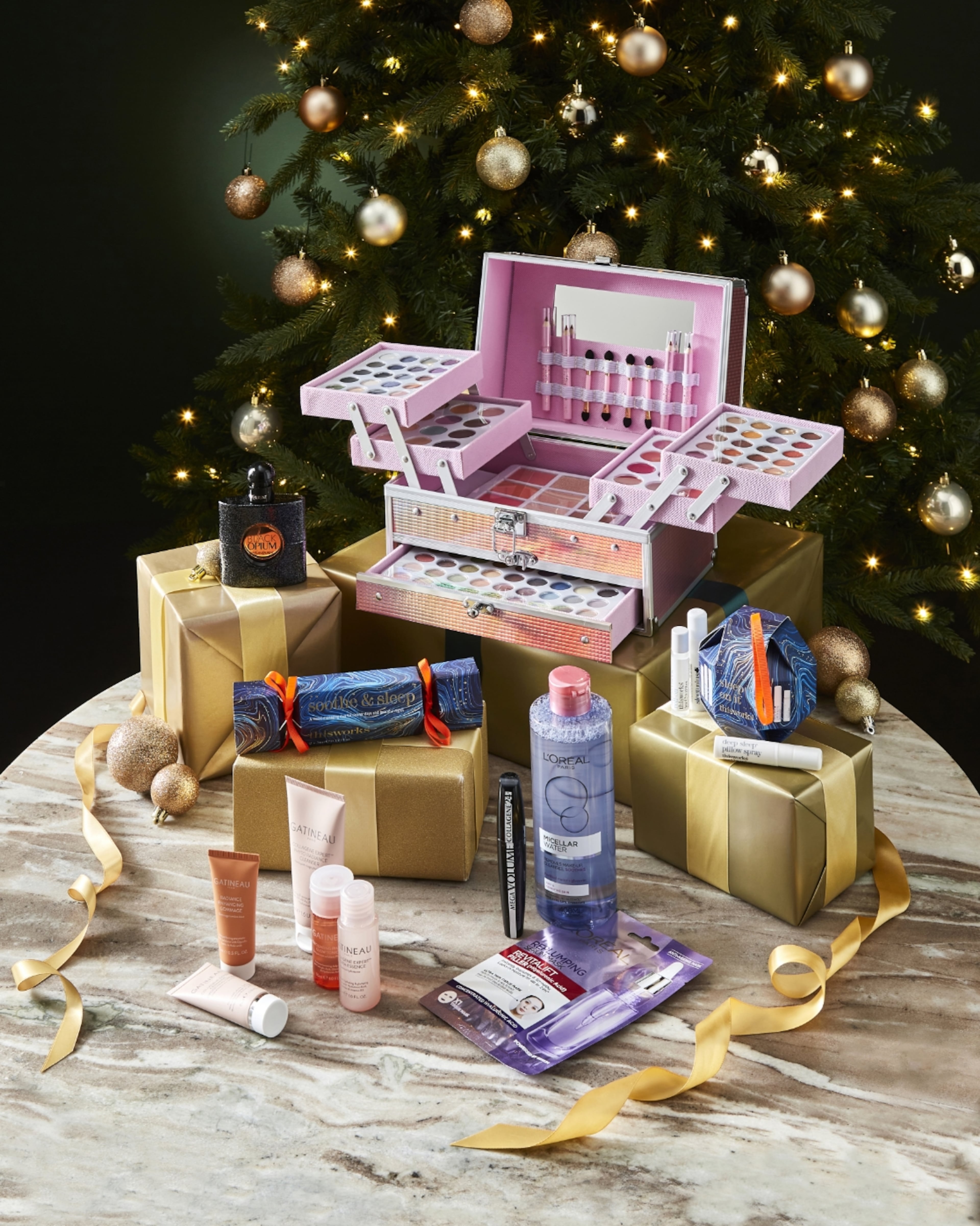 Makeup and beauty gift sets for Christmas, including a large pink cosmetics case, skincare products, and Black Opium perfume.