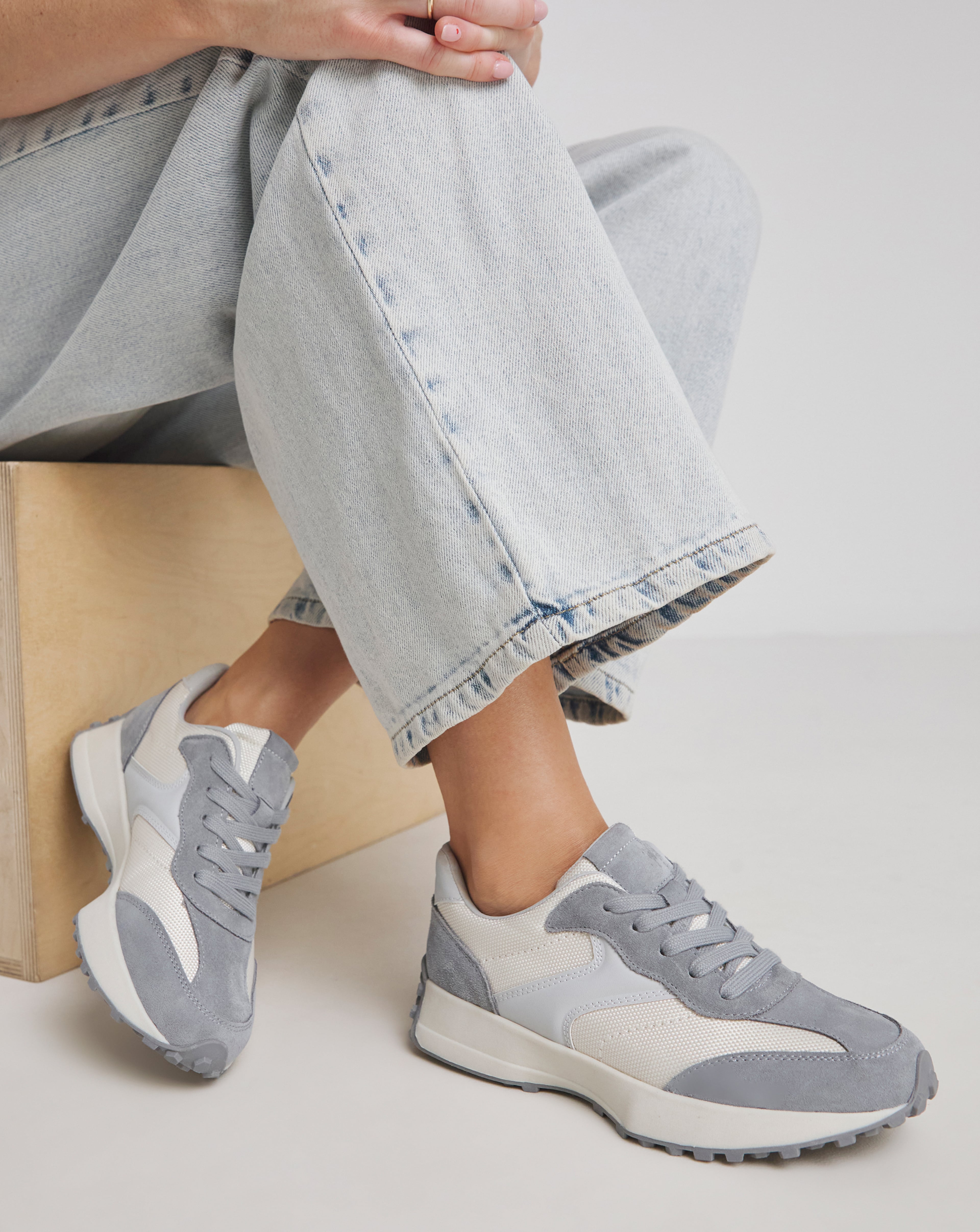Close-up of a model wearing grey Akira suede trainers