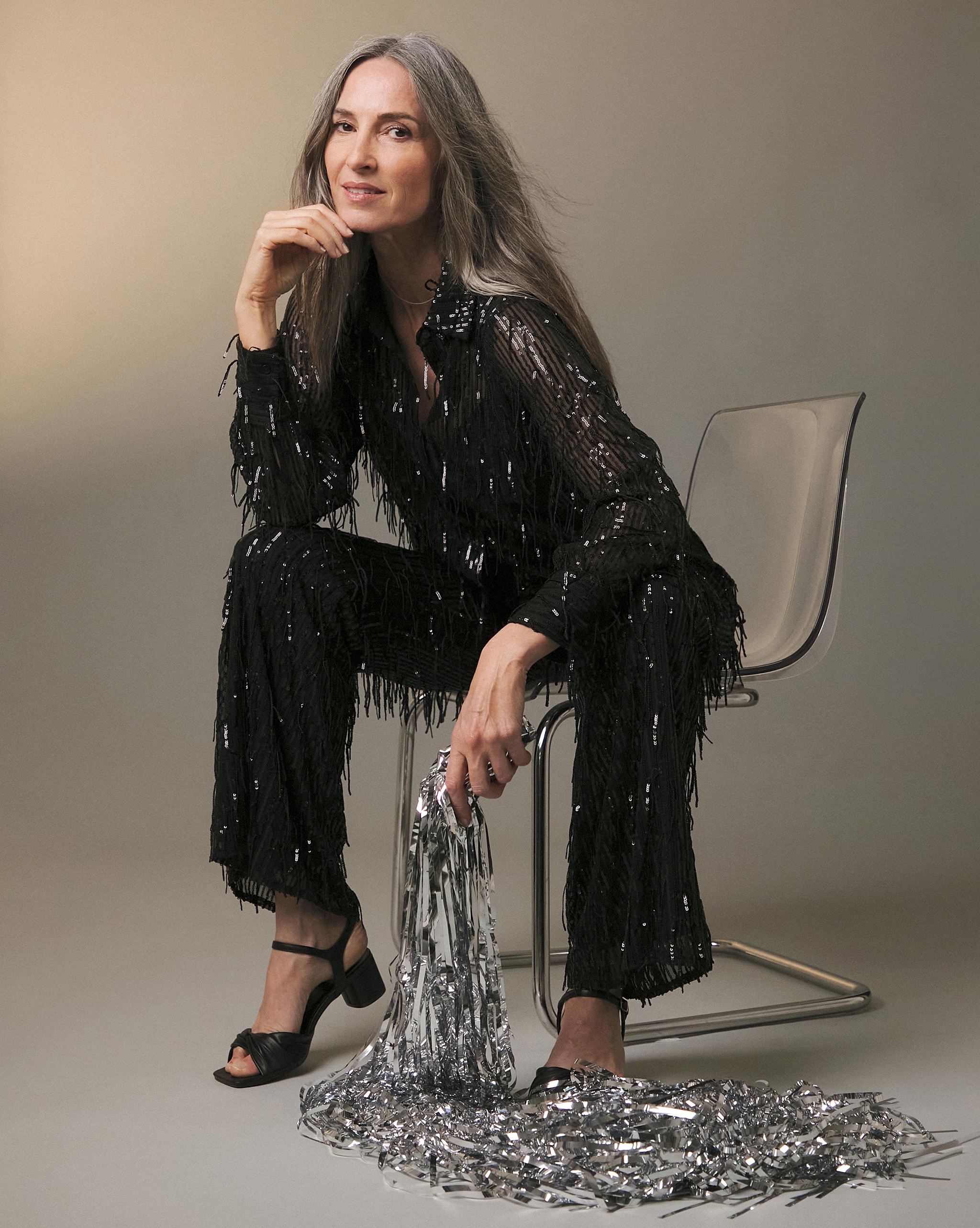 A woman sat on a chair wearing a black jumpsuit