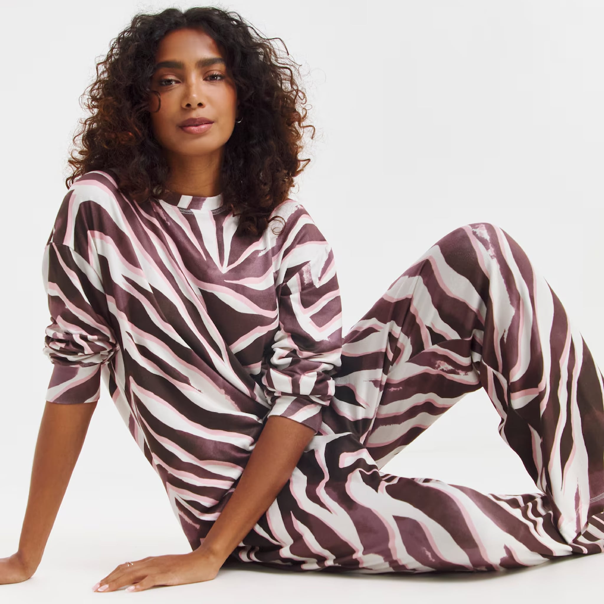 A model sat on the floor wearing a zebra print loungewear set