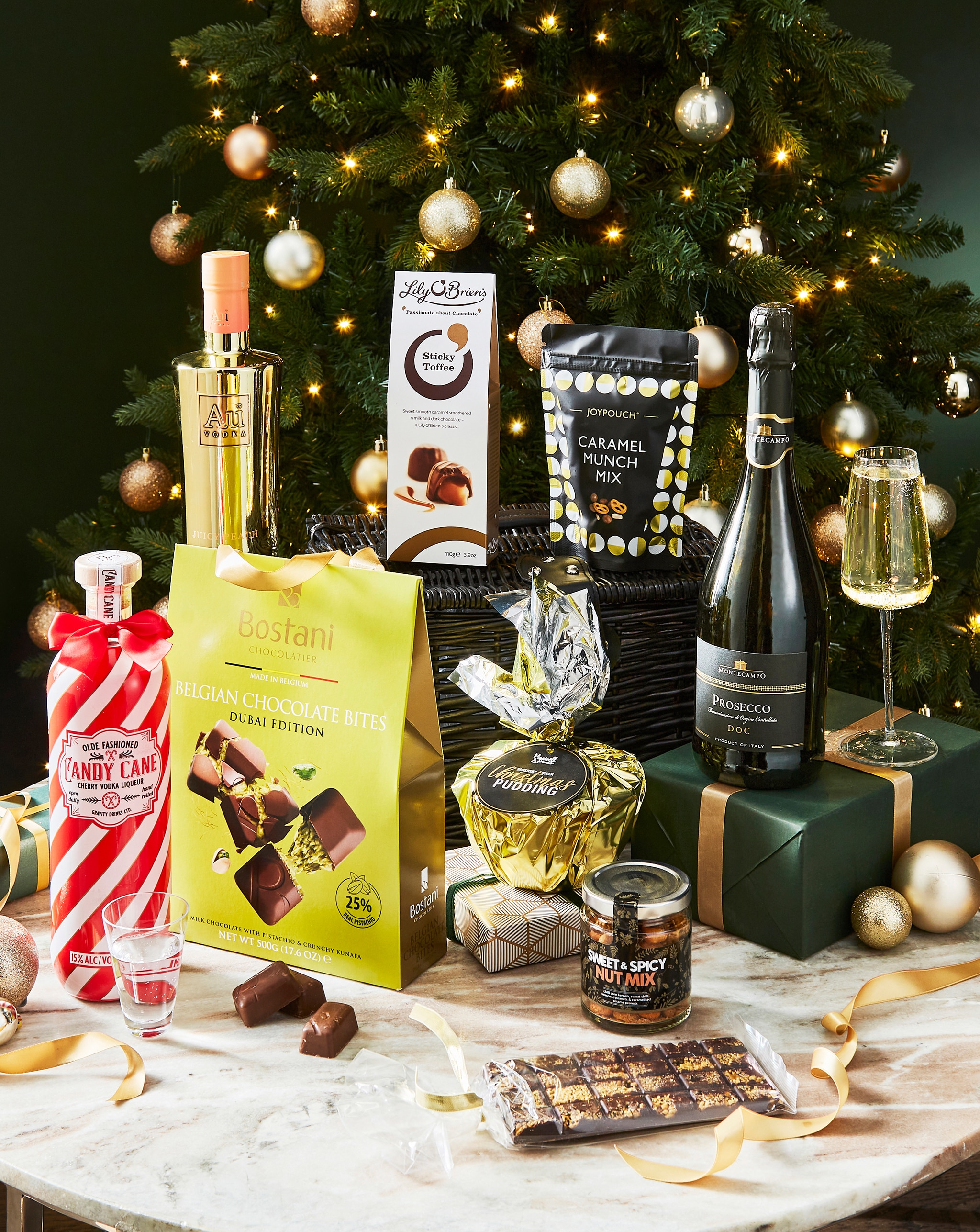 A selection of food and drink on a table, in front of a Christmas tree.