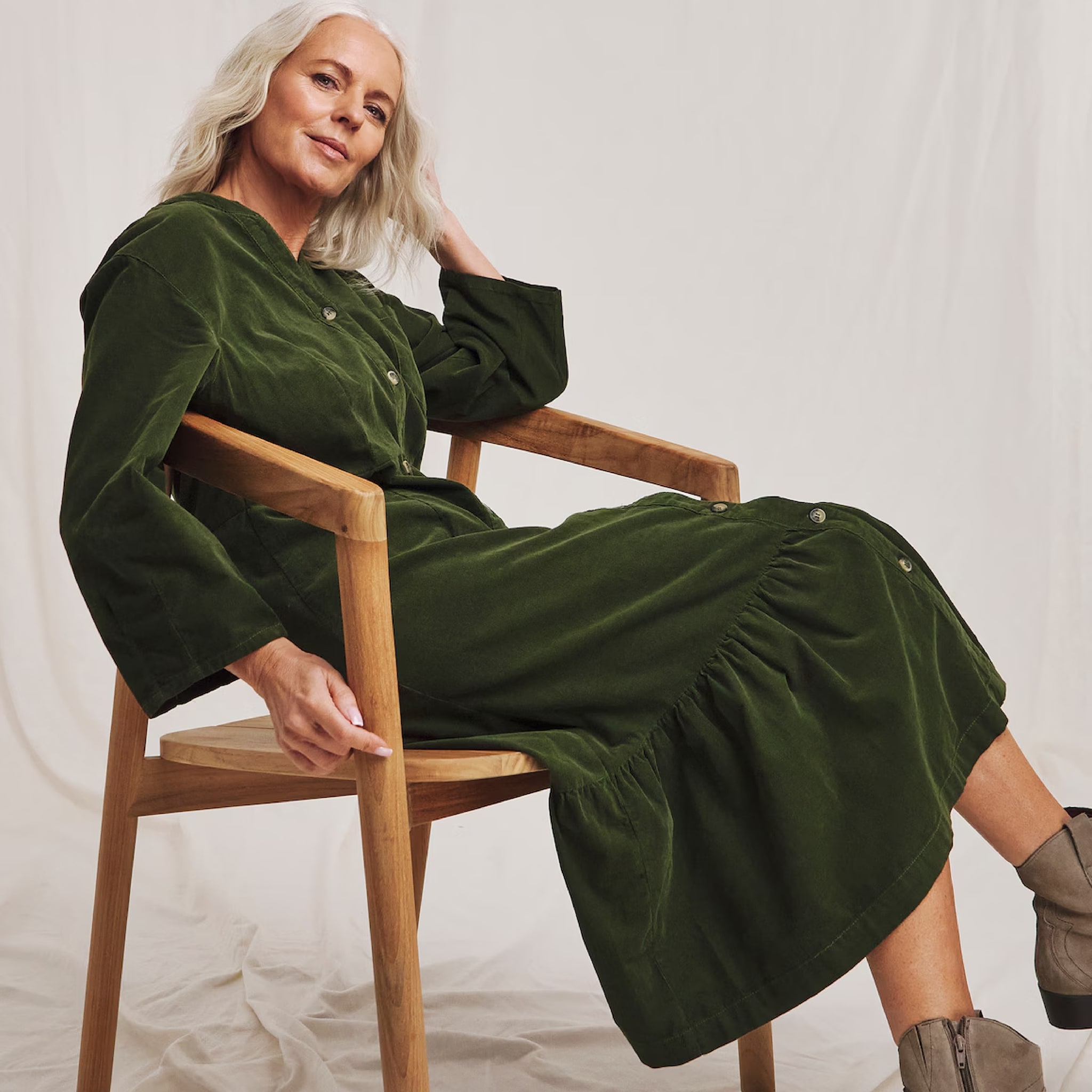 A woman sat in a chair wearing a dark green dress