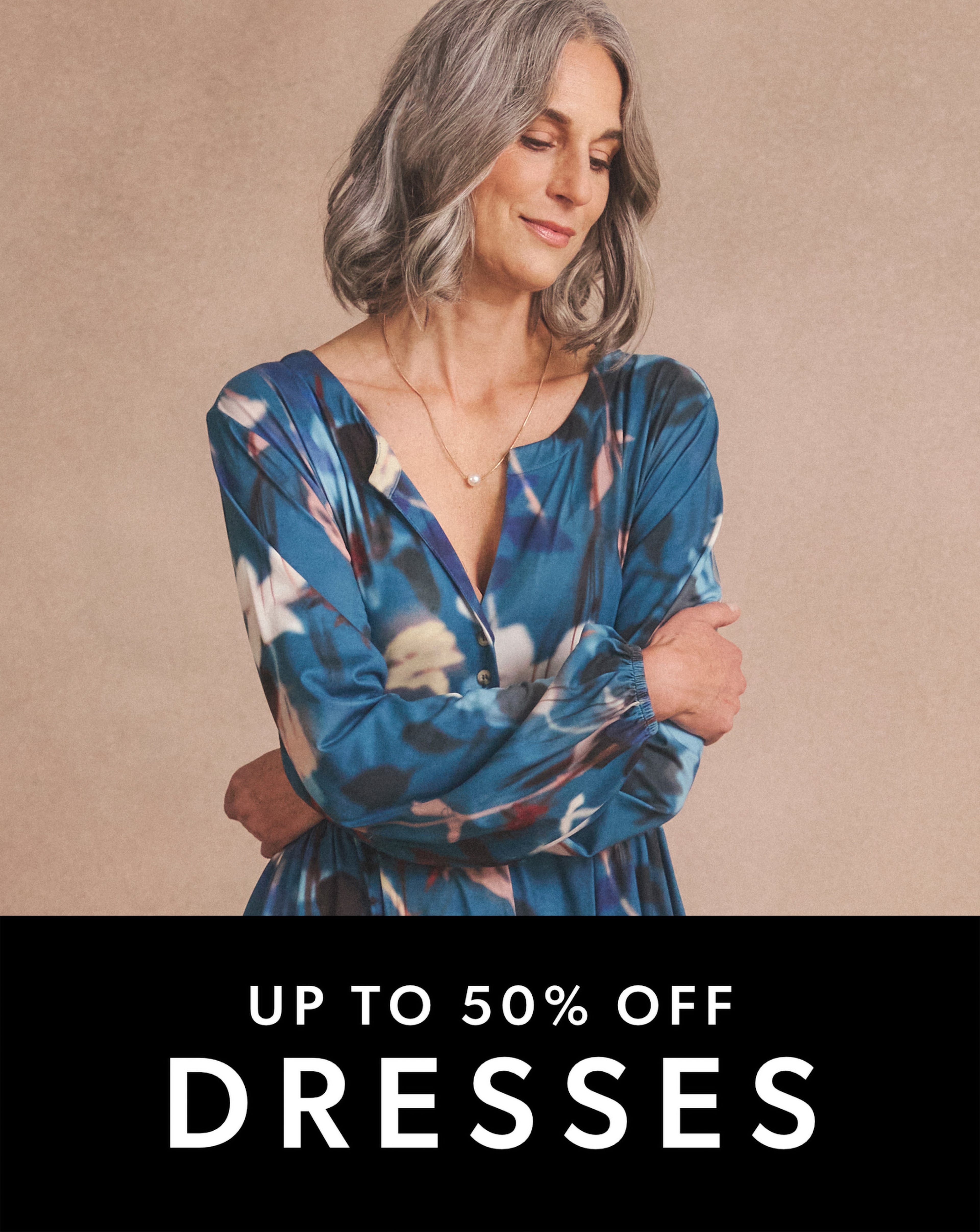 A person wearing a long-sleeved, blue dress with a colourful abstract floral pattern.