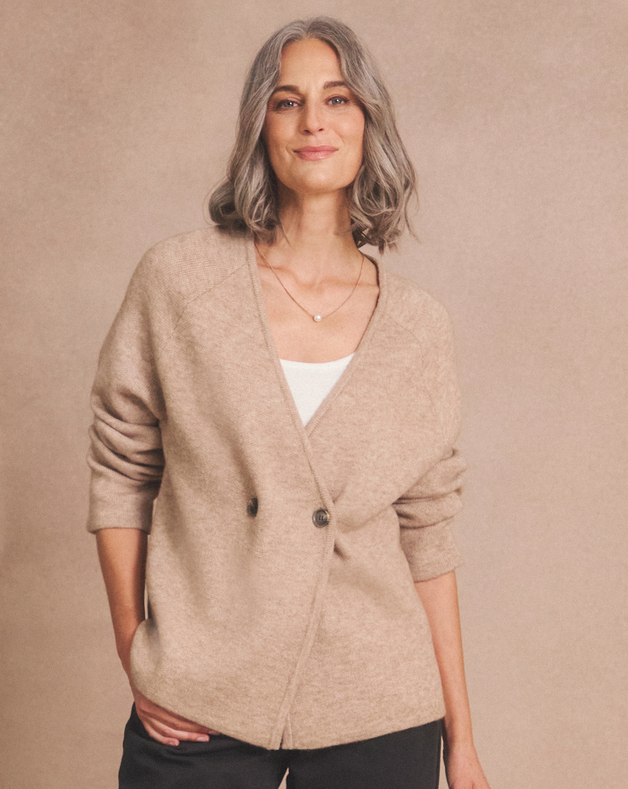 Person wearing a beige cardigan over a white top.