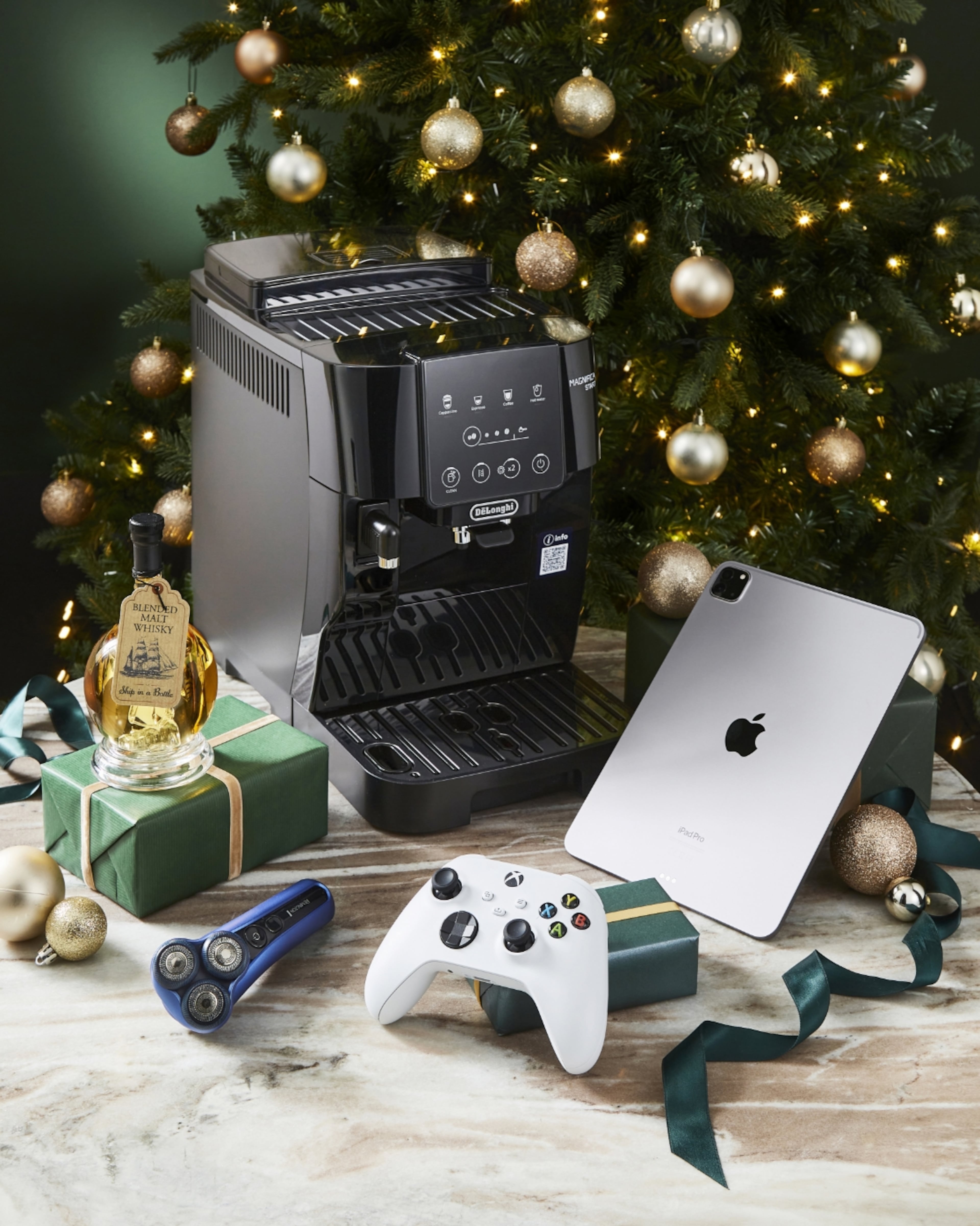 Luxury tech and appliance gifts: De'Longhi coffee machine, Apple iPad Pro, Xbox controller, and whisky bottle.