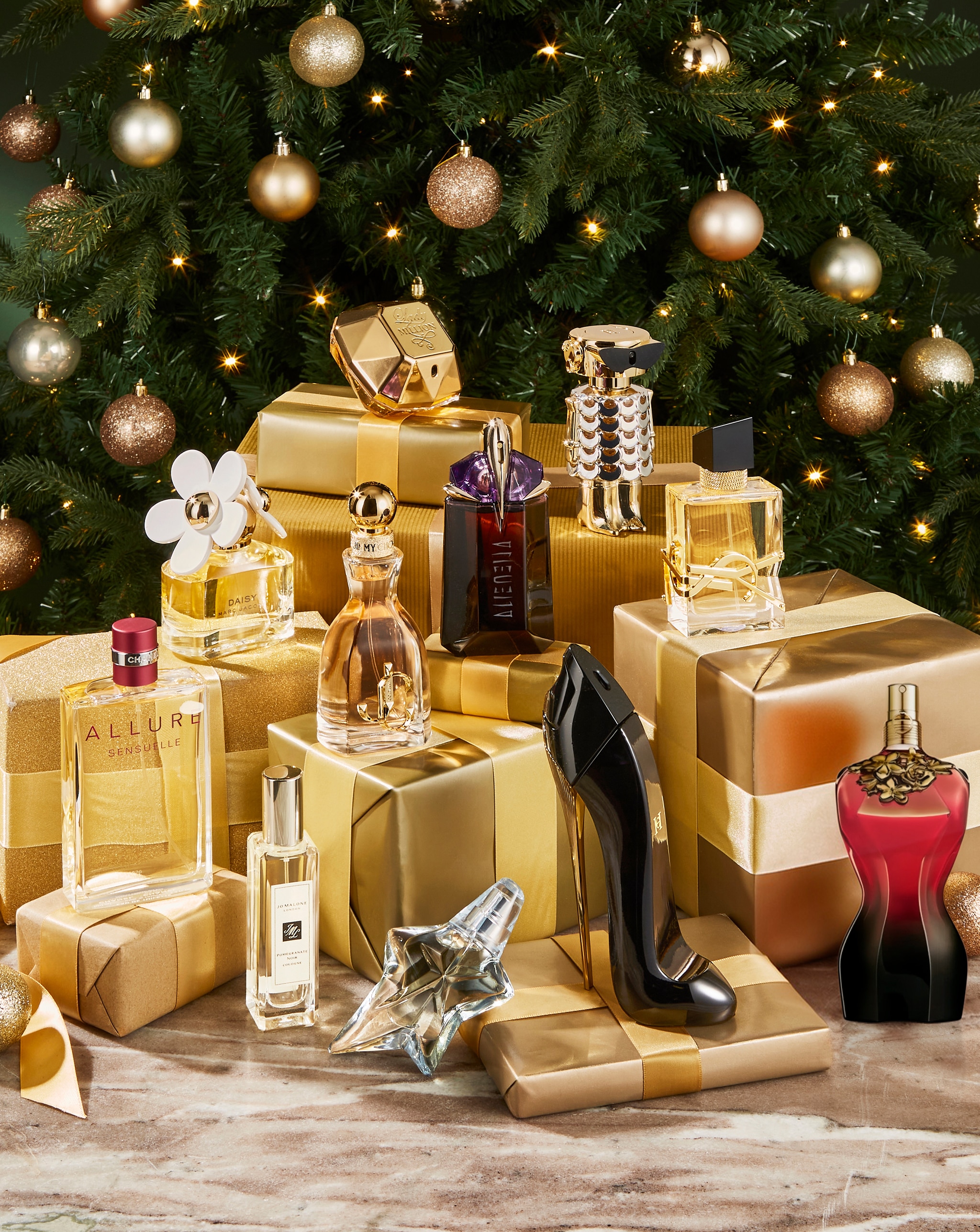Festive display of perfume bottles with a Christmas tree in the background.
