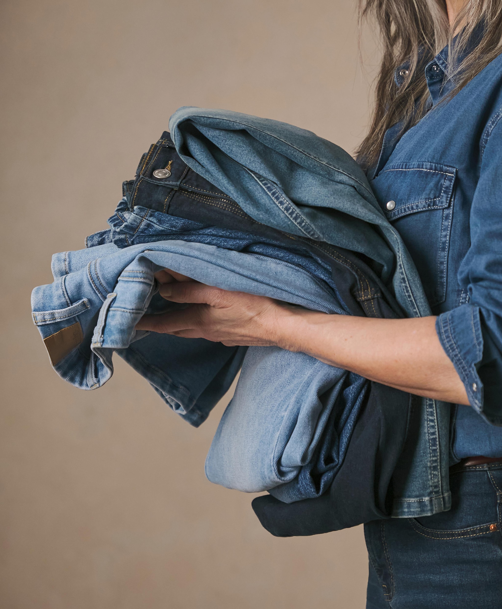 A woman holding pile of denim jeans