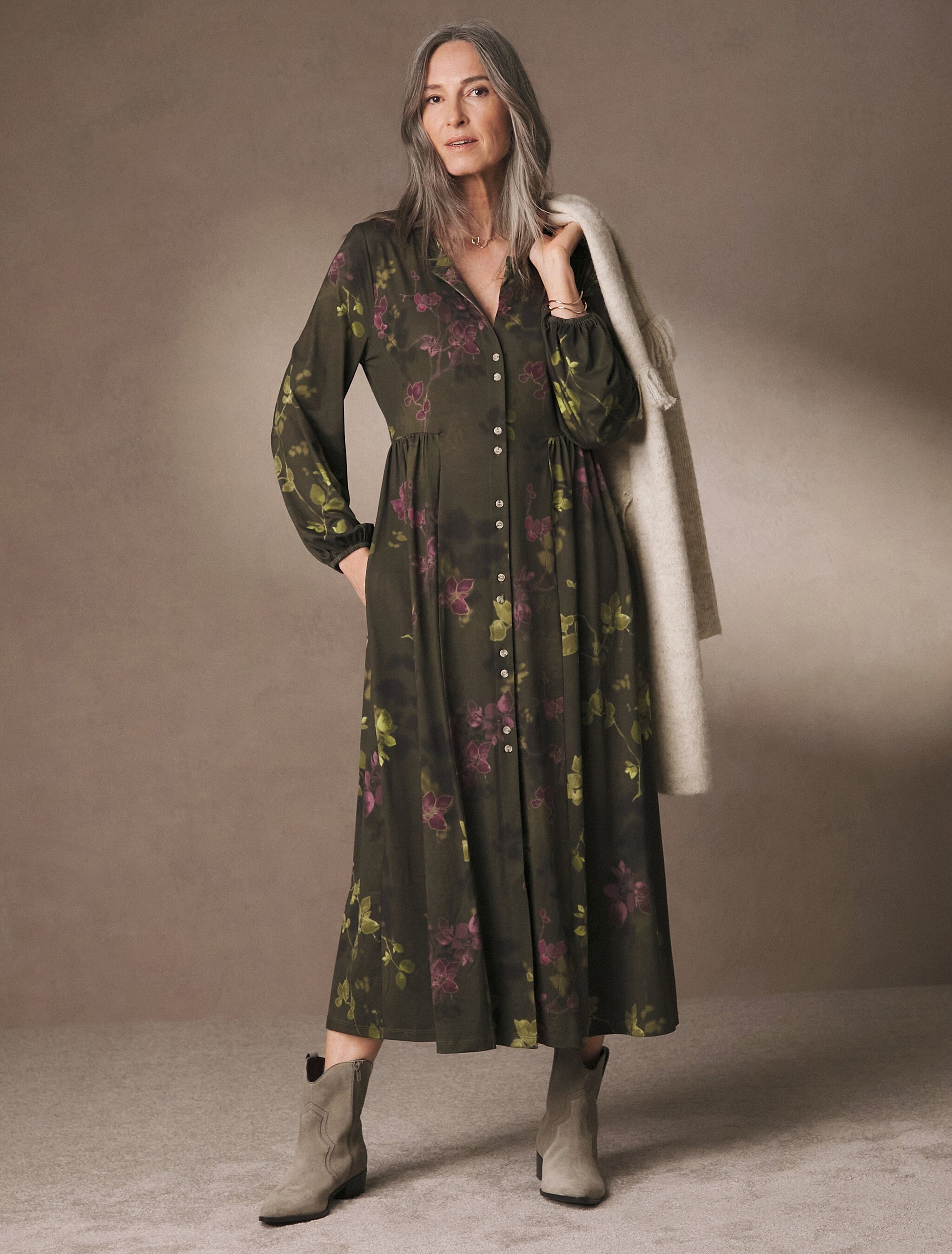 Model stood wearing a dark green calf length dress