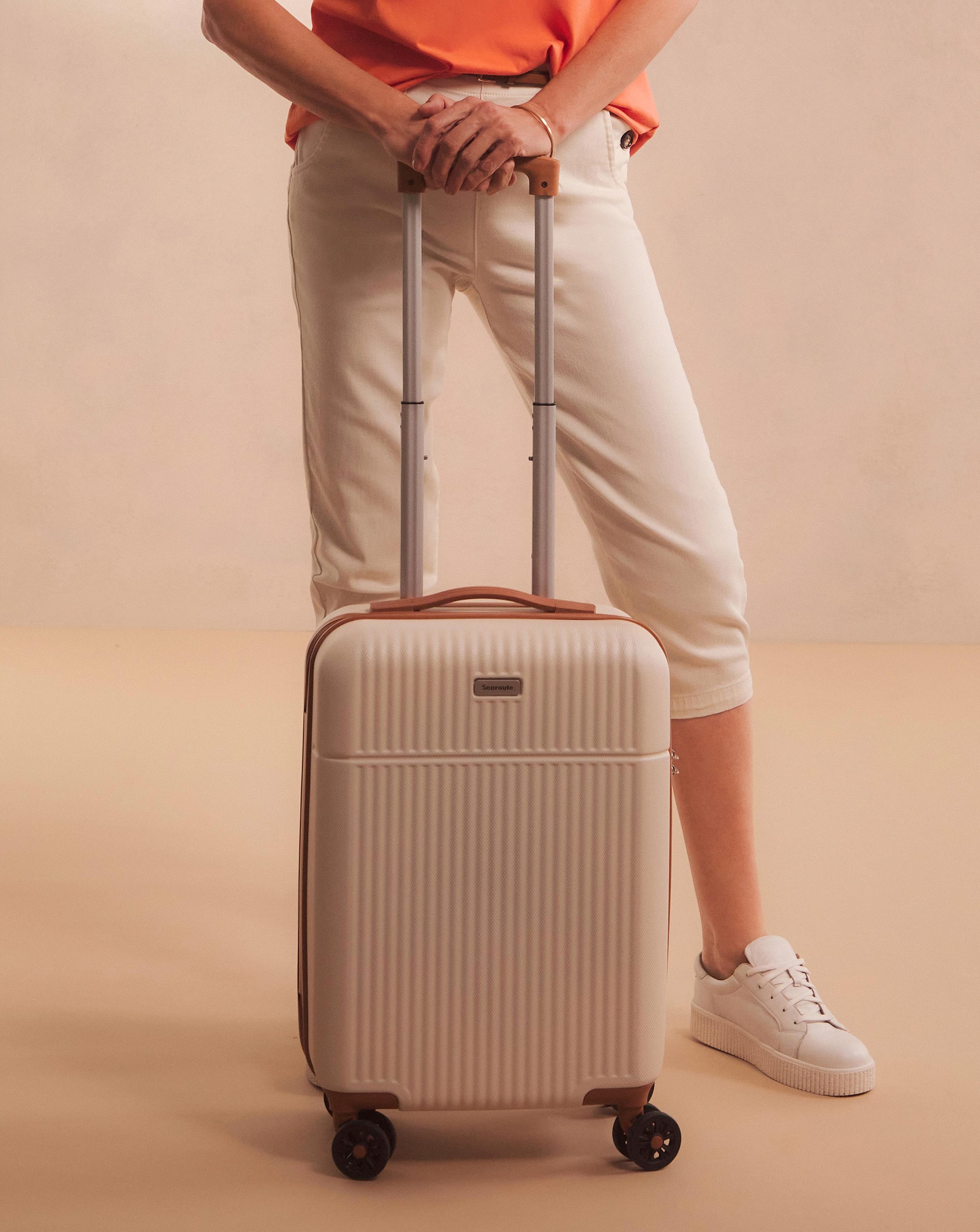Model stood with a light coloured suitcase