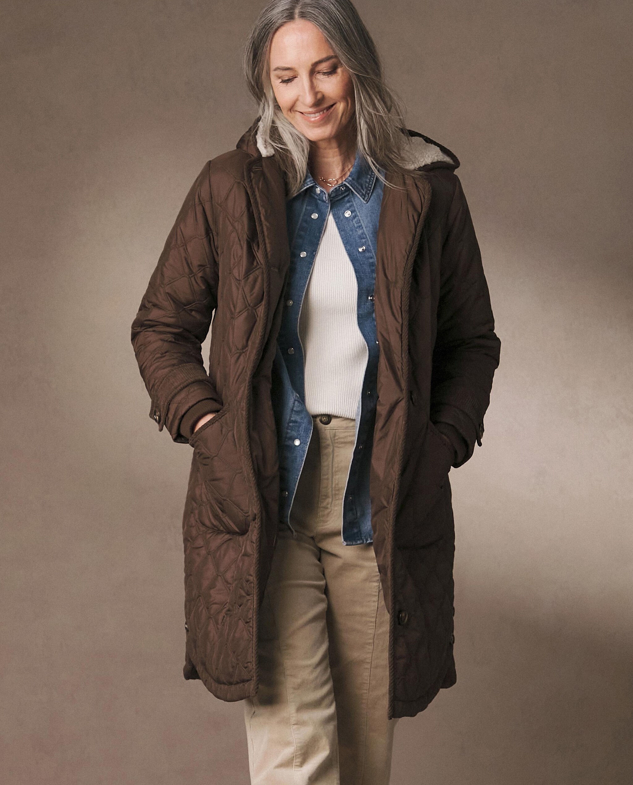 A woman stood wearing a long brown winter coat