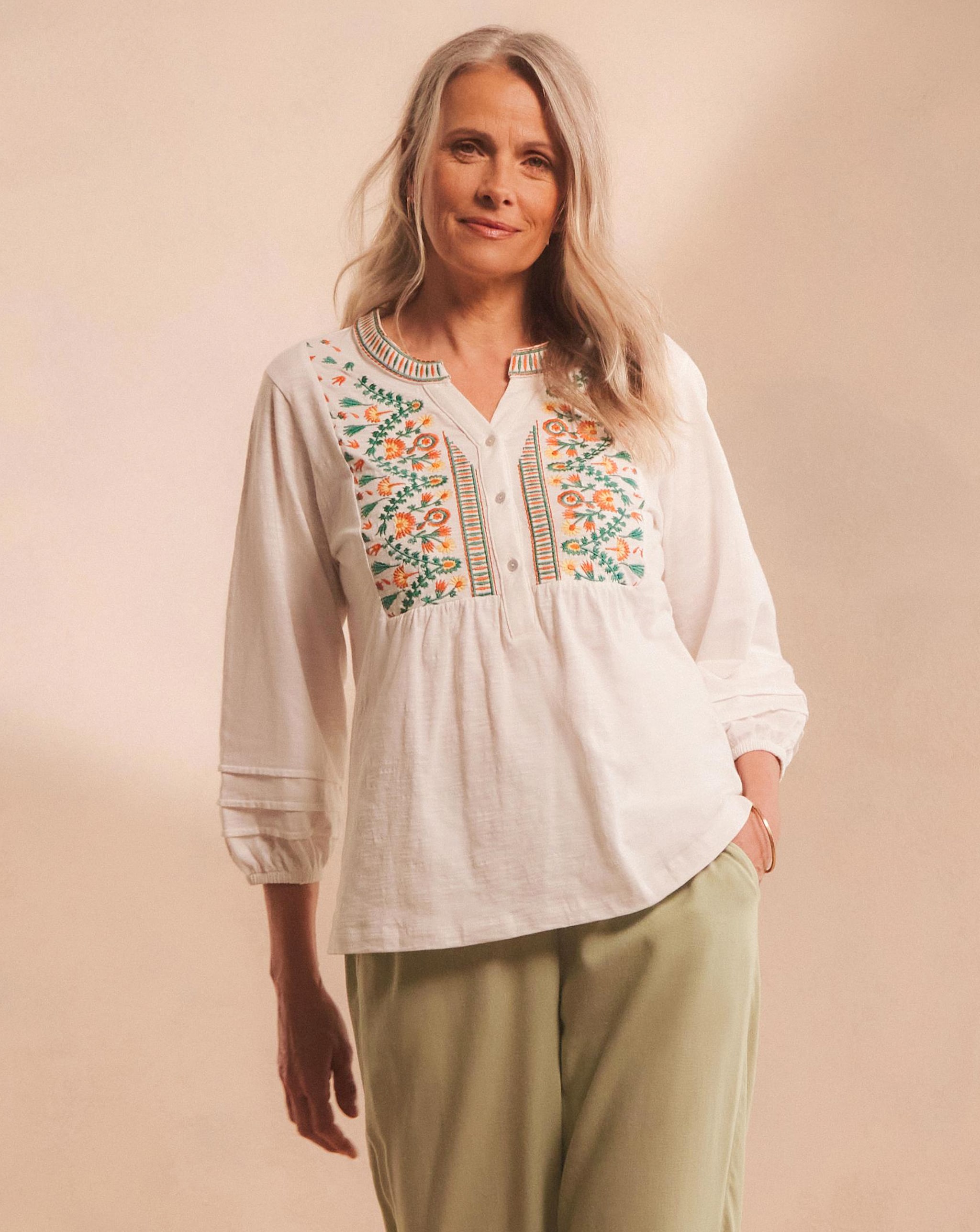 Model wearing a light coloured top with a floral pattern