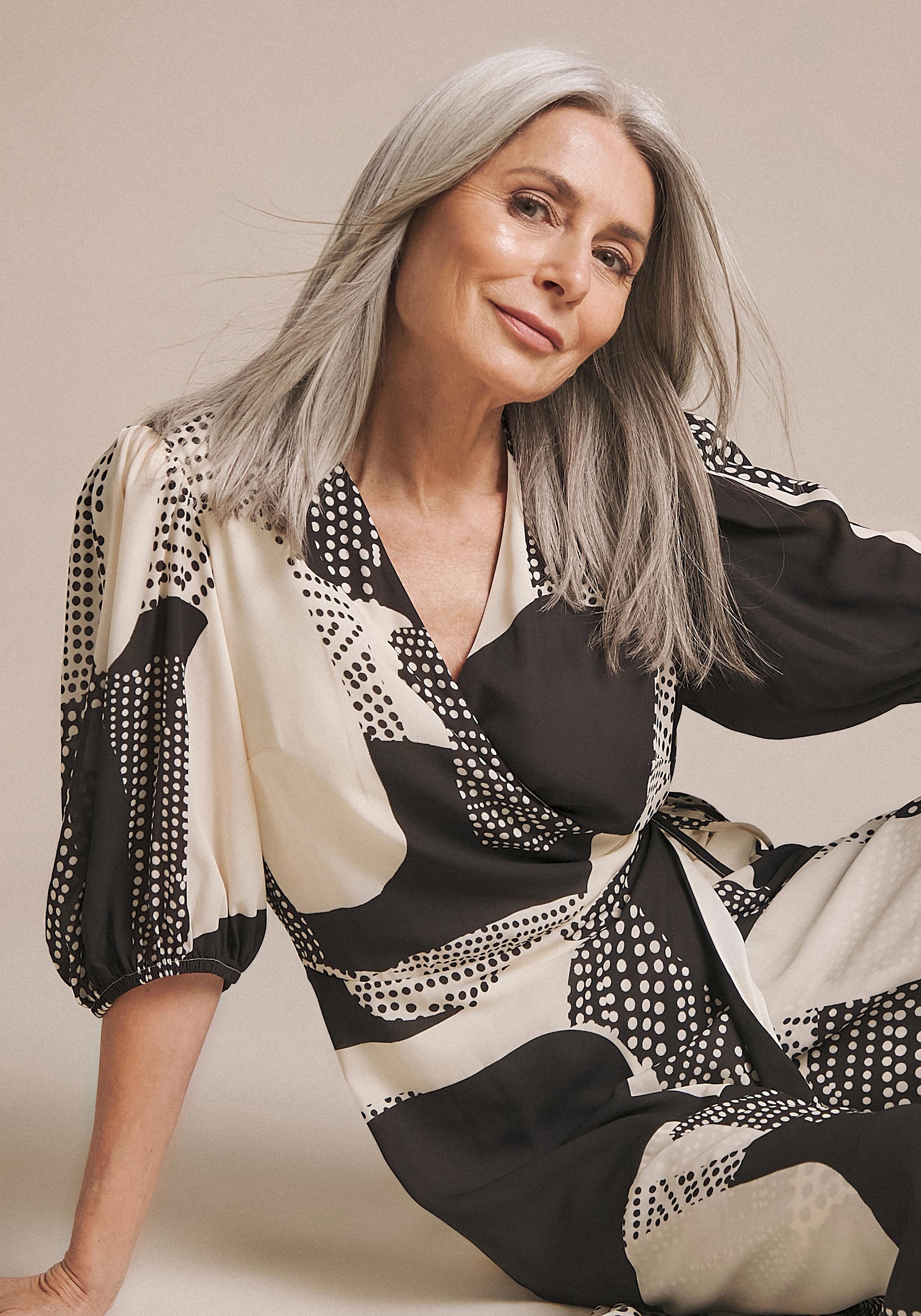 A woman sat wearing a black and beige patterned dress